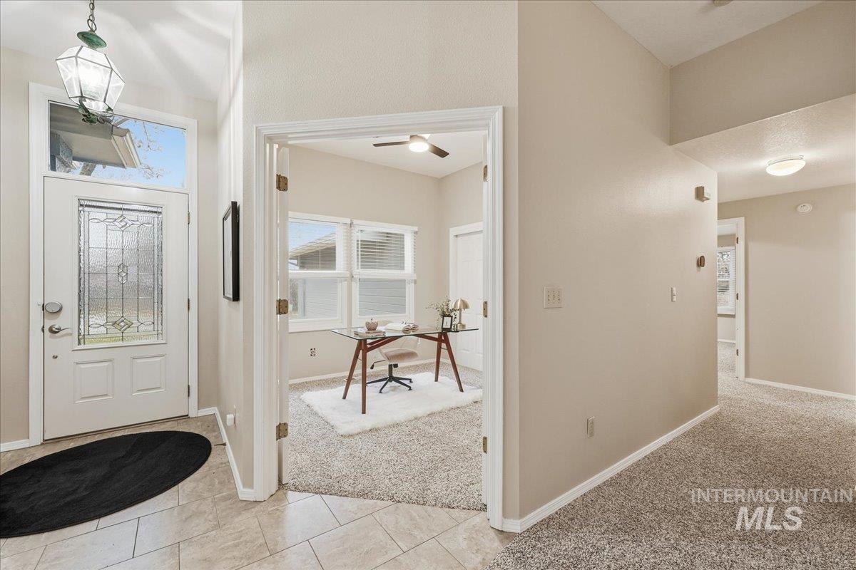 Foyer entrance with light carpet and light tile patterned floors