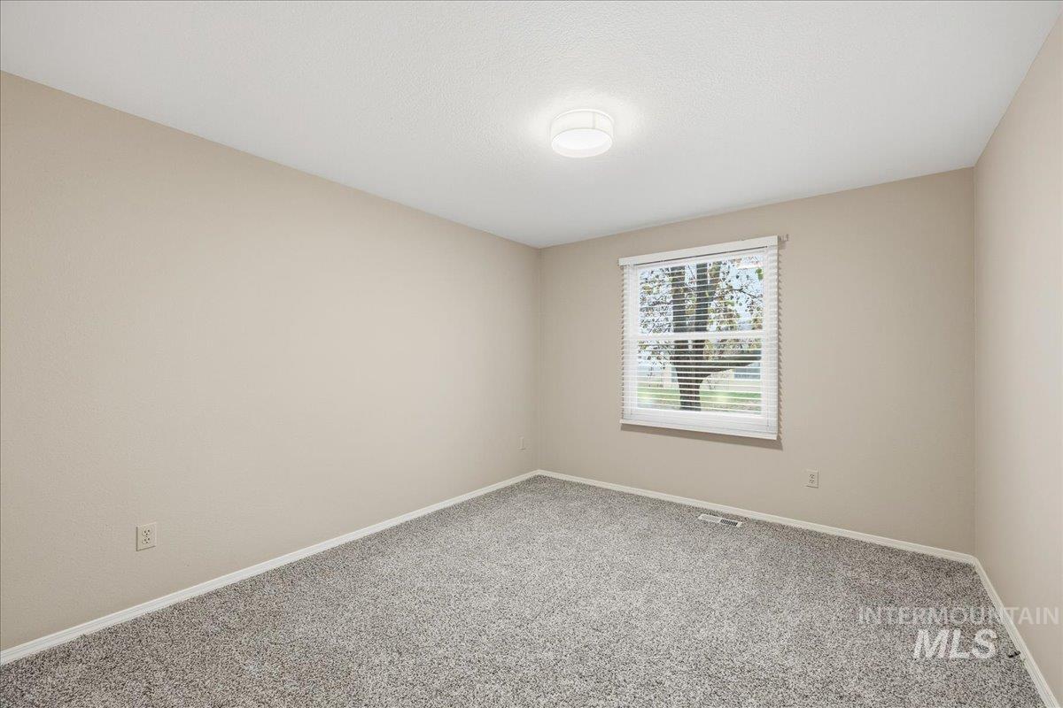 Carpeted spare room featuring baseboards