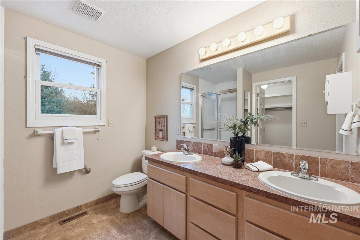 Bathroom featuring double vanity, a stall shower, and a textured ceiling