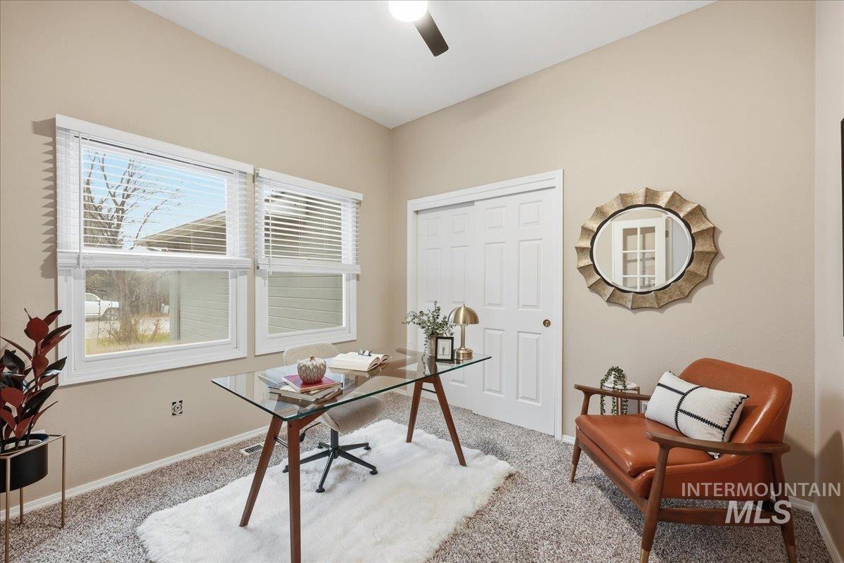 Carpeted office with baseboards and a ceiling fan