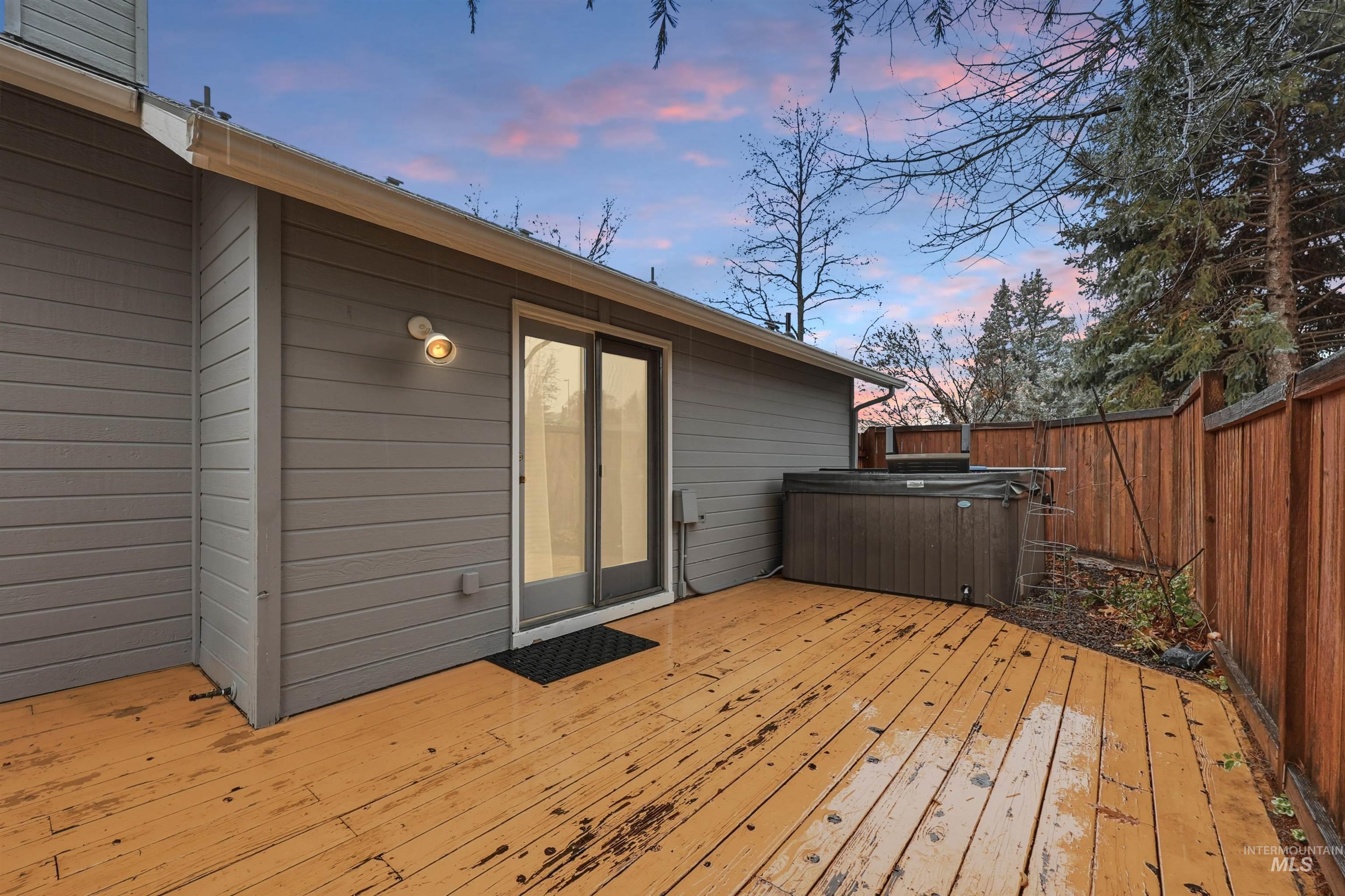 Wooden terrace with a fenced backyard and a hot tub