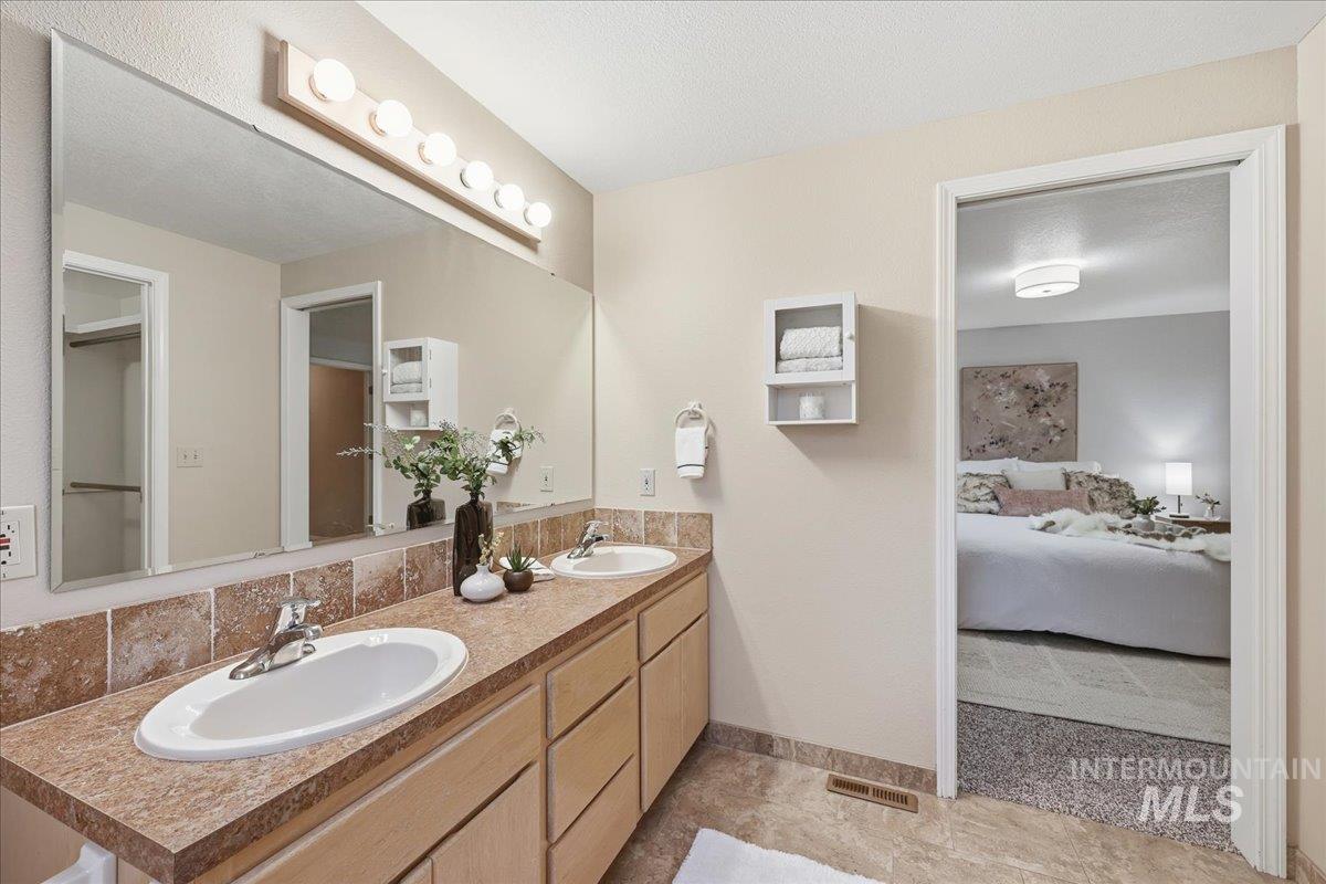 Ensuite bathroom featuring double vanity and a textured ceiling