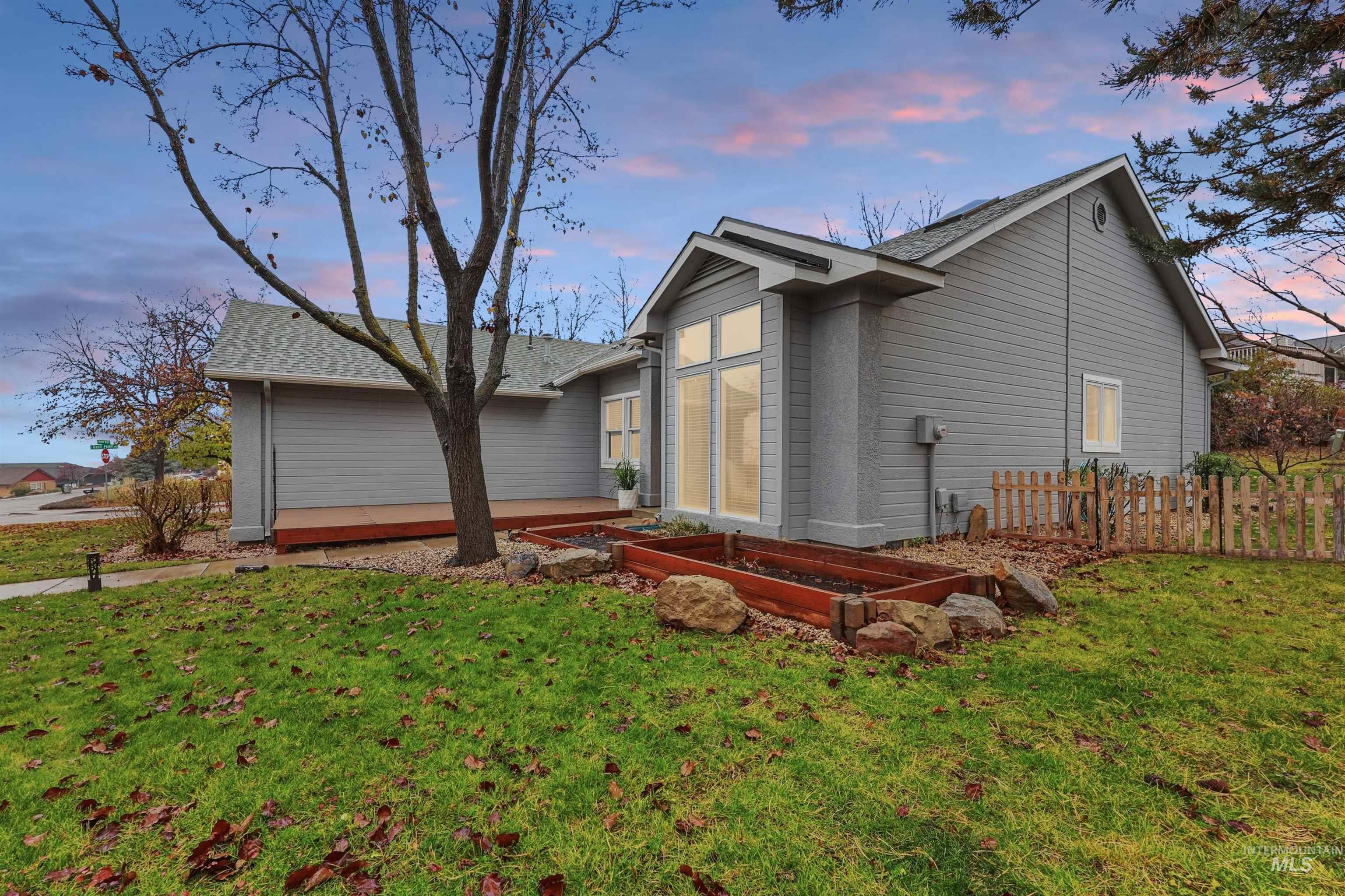 Property exterior at dusk with a lawn, a garden, and a shingled roof