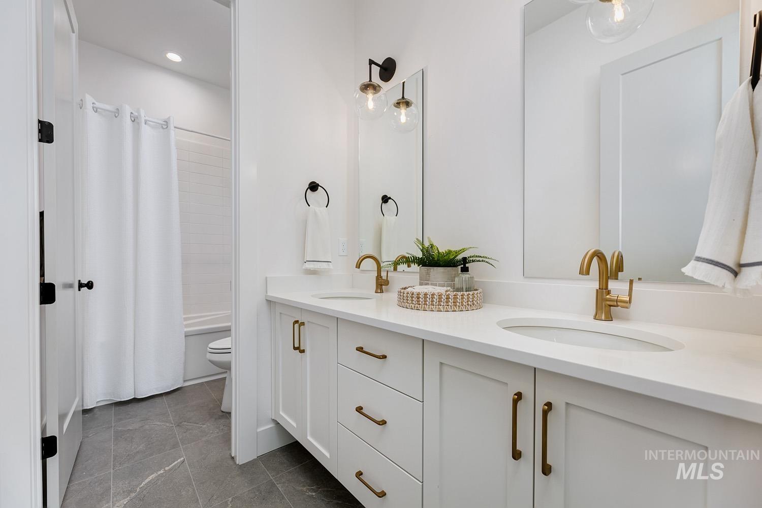 Full bath featuring shower / bathtub combination with curtain, double vanity, and dark tile patterned floors