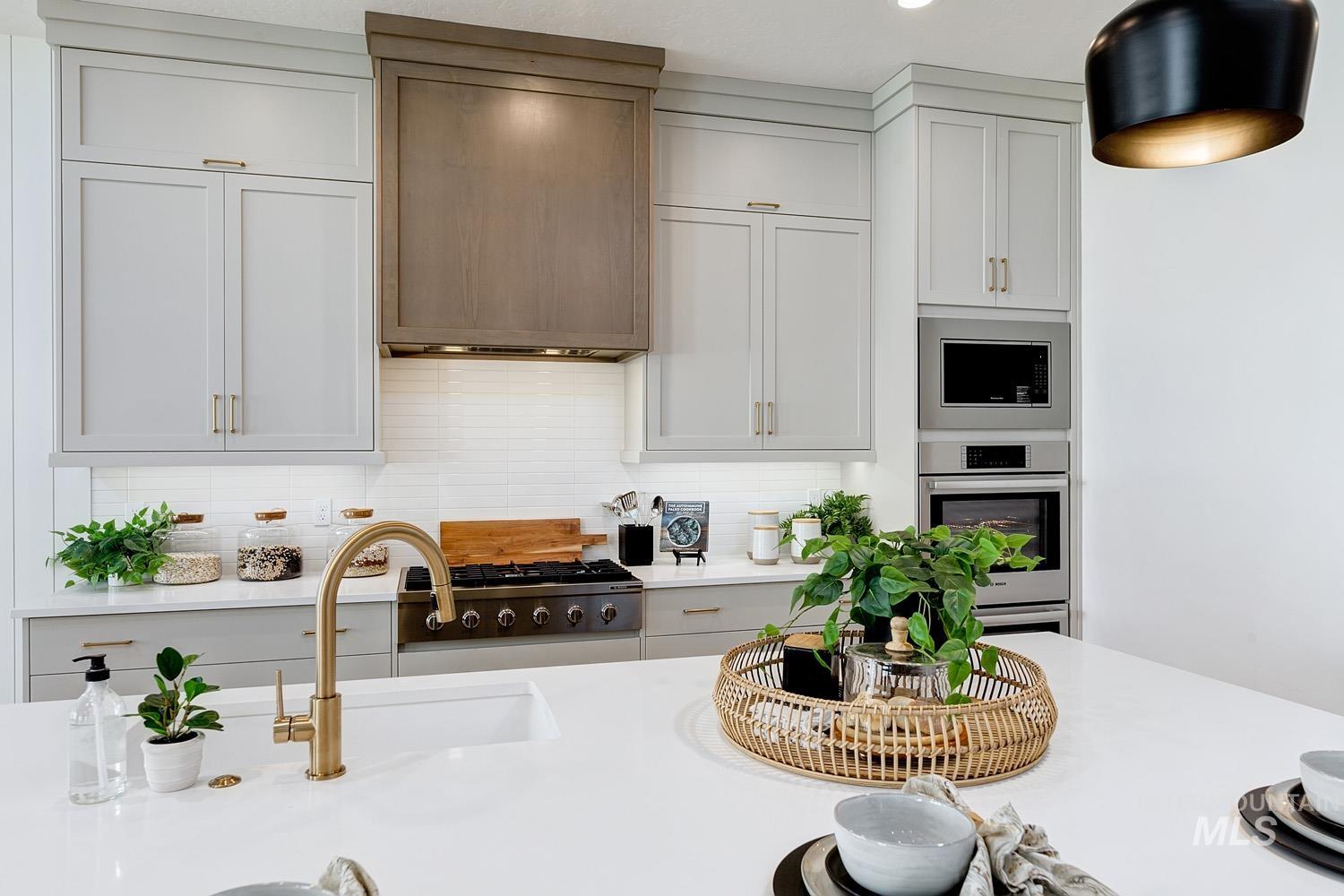 Kitchen featuring decorative backsplash, white cabinetry, stainless steel appliances, and light stone countertops