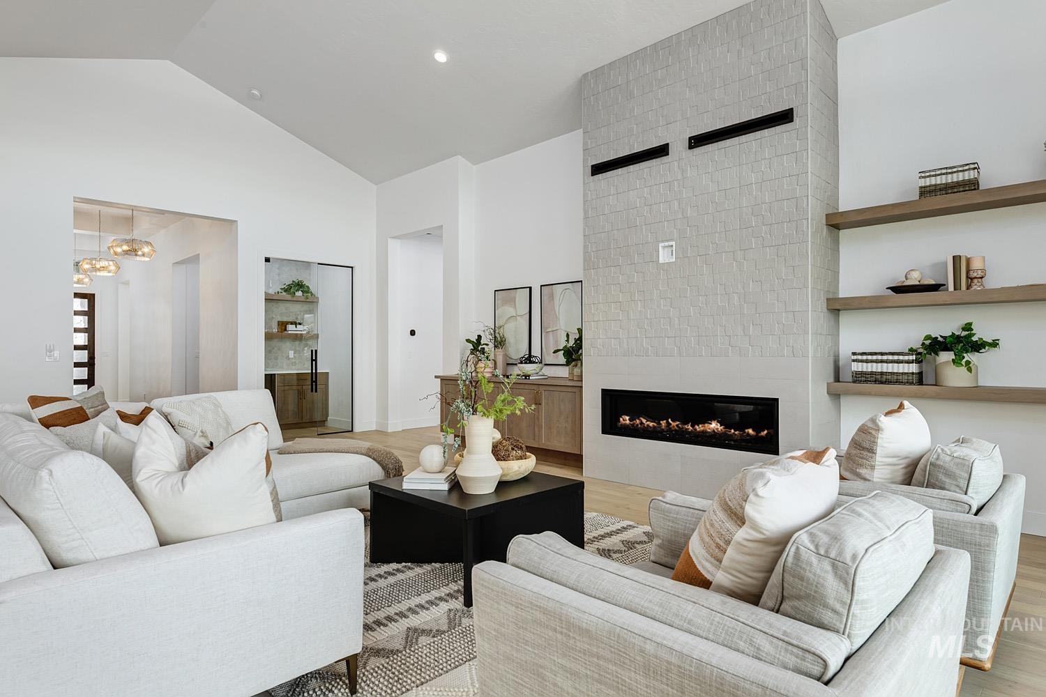 Living room with a tiled fireplace, light wood-type flooring, high vaulted ceiling, and recessed lighting