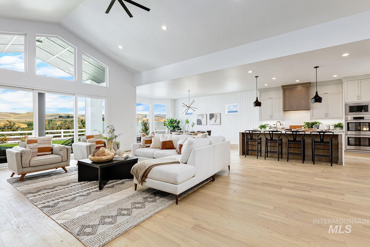 Living area featuring light wood-style floors, a chandelier, high vaulted ceiling, recessed lighting, and a ceiling fan