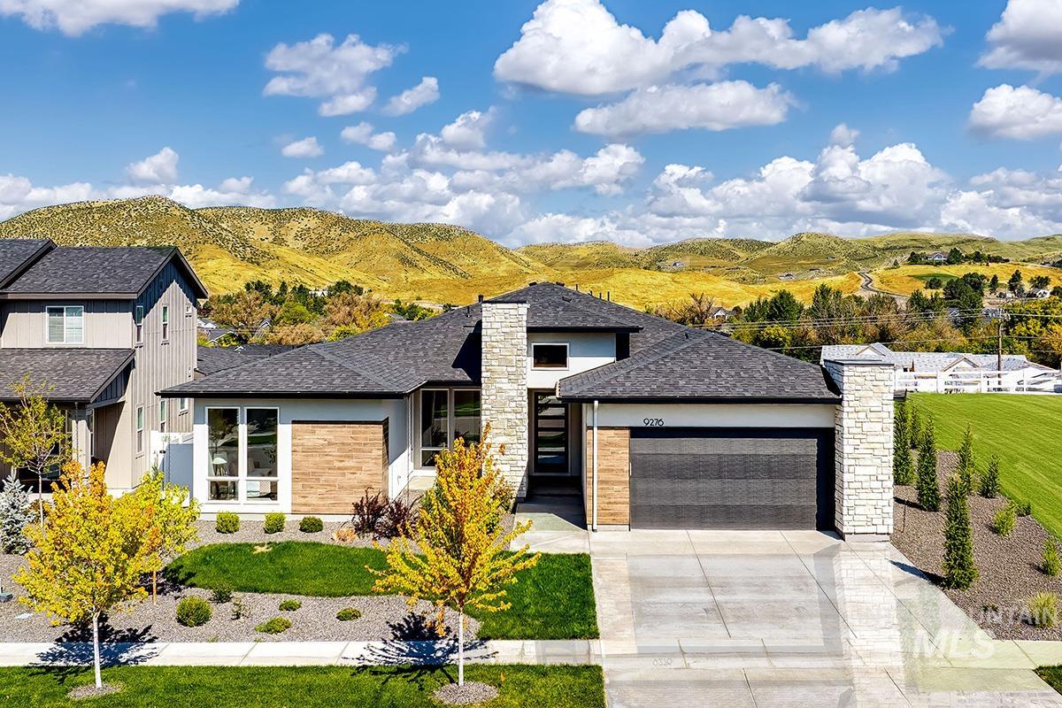 View of front of home featuring a garage, roof with shingles, driveway, stucco siding, and a front yard
