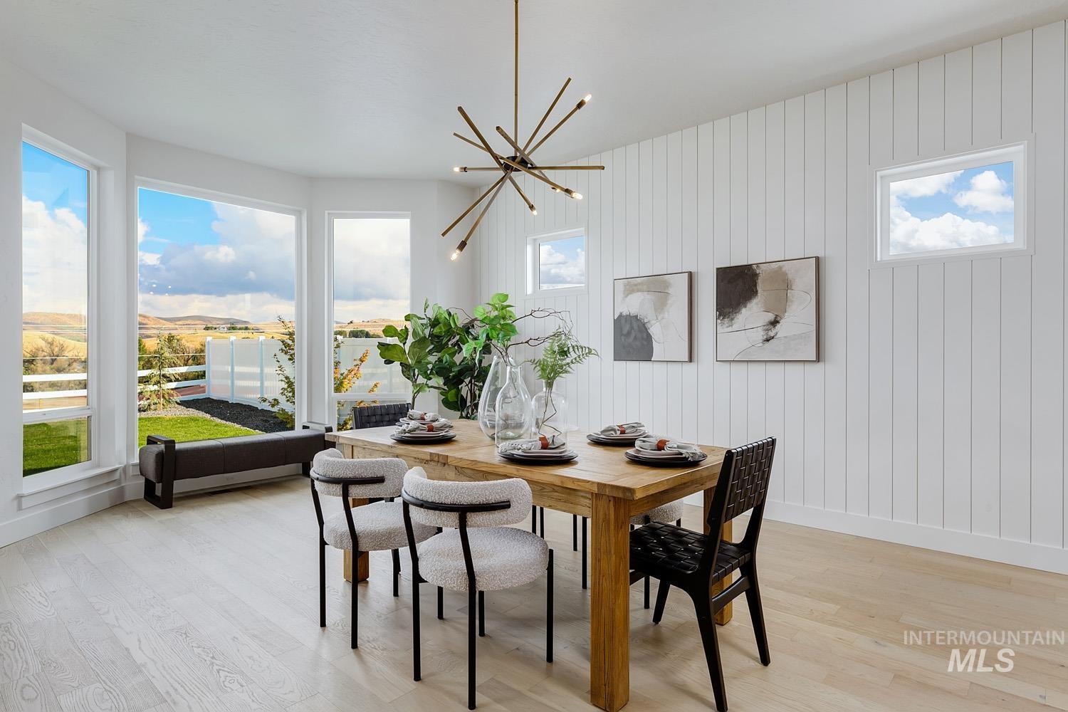 Dining area with light wood-style flooring, wood walls, and a chandelier