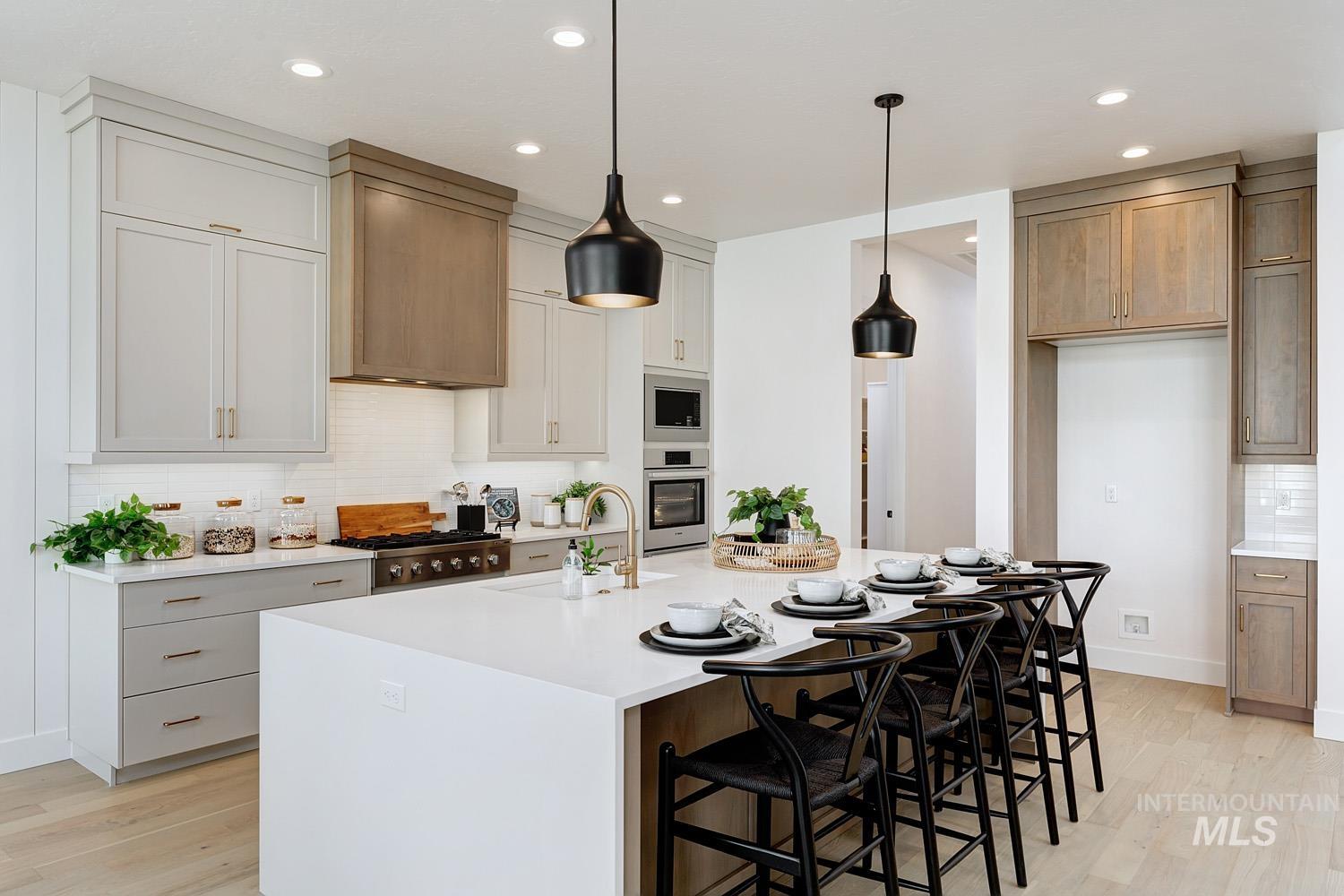 Kitchen with tasteful backsplash, a breakfast bar, light wood-style floors, pendant lighting, and light stone counters