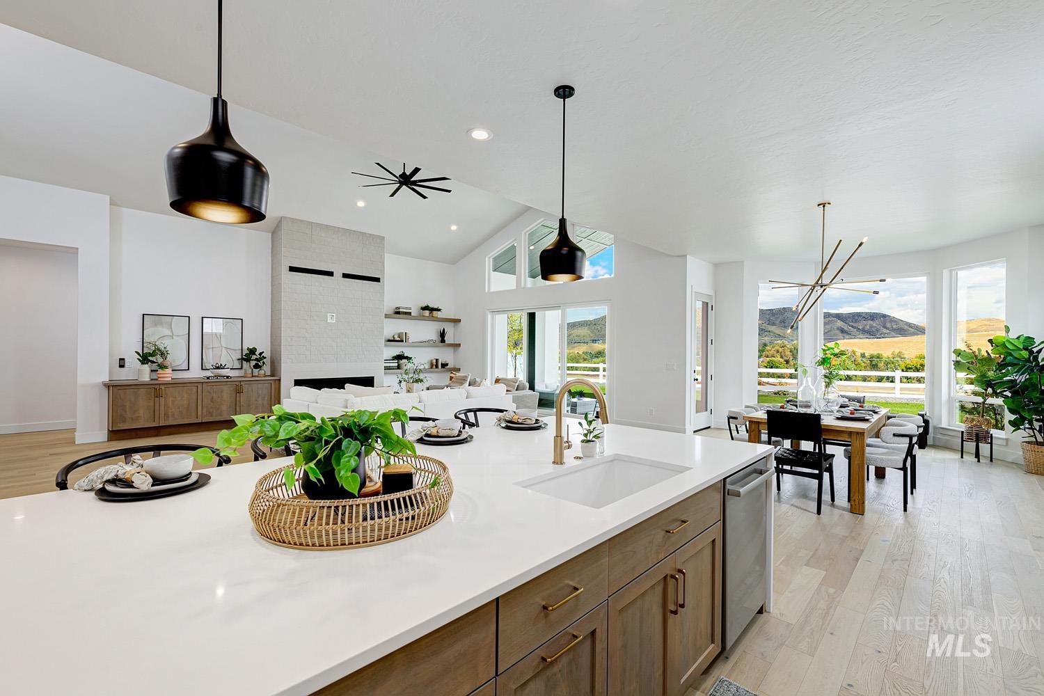 Kitchen with light wood finished floors, decorative light fixtures, brown cabinetry, open floor plan, and light stone countertops