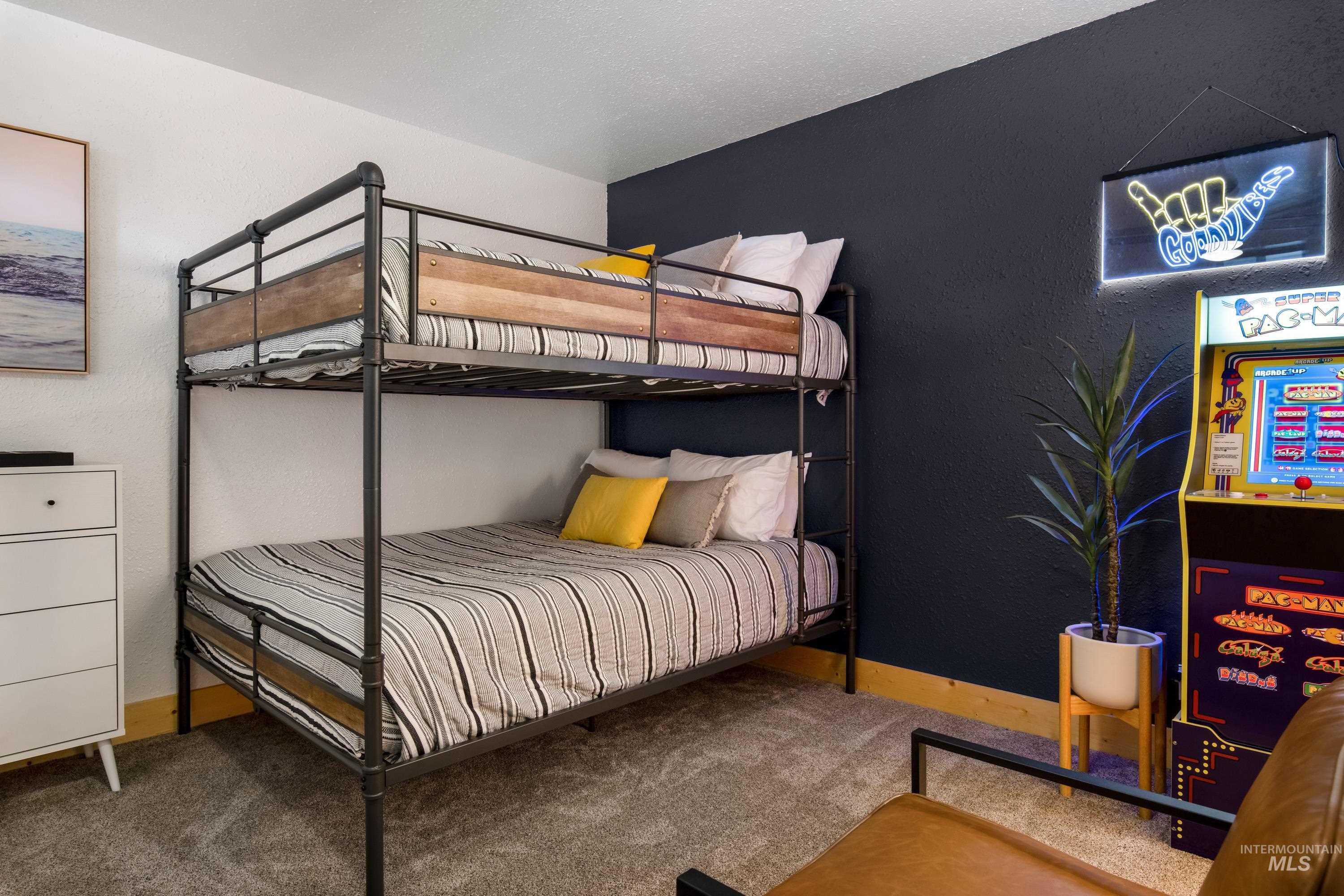 Carpeted room featuring a two-tier bunk bed with industrial-style metal framing and wood-finish accents