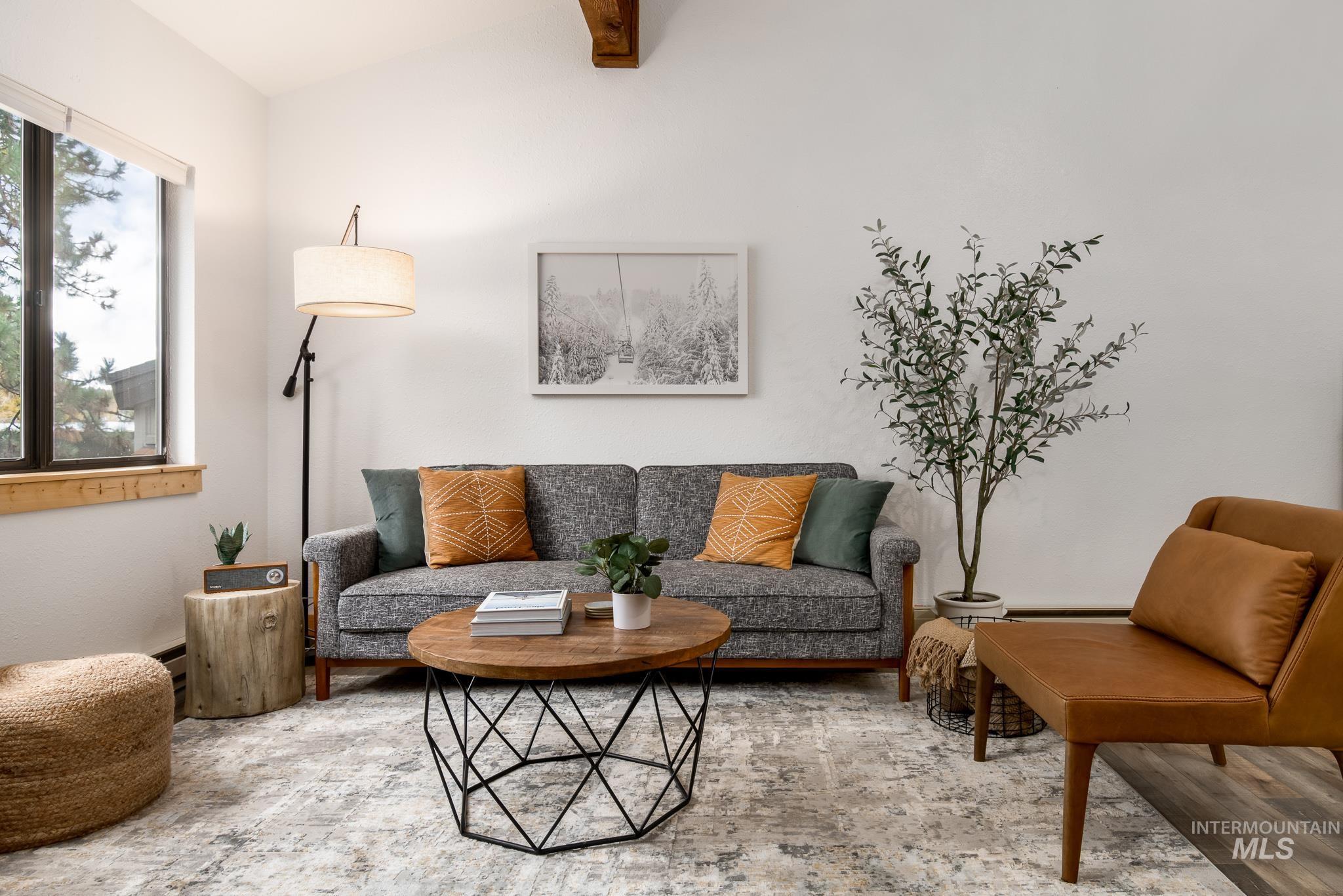 Living area featuring an exposed wood beam, large window with wood trim, and light-toned walls