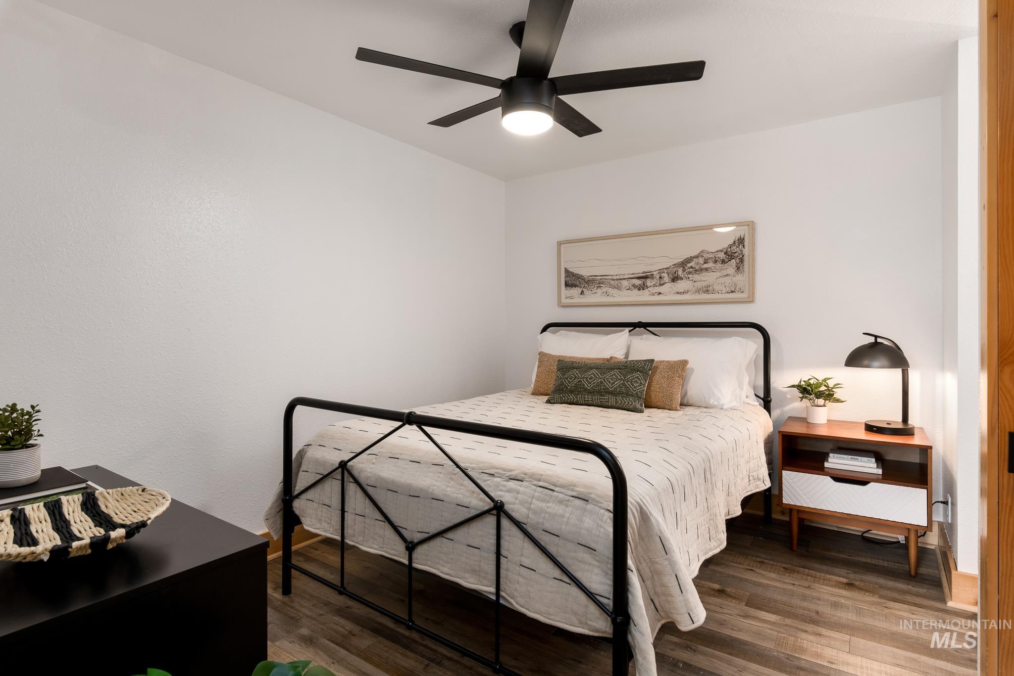 Bedroom featuring wood-finish flooring, a contemporary ceiling fan with integrated lighting, and a light wood-tone door frame
