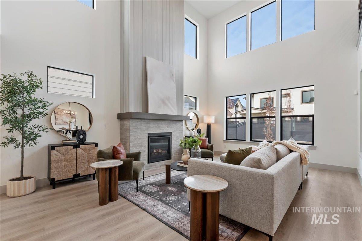 Living area with light wood finished floors, a glass covered fireplace, plenty of natural light, and a high ceiling