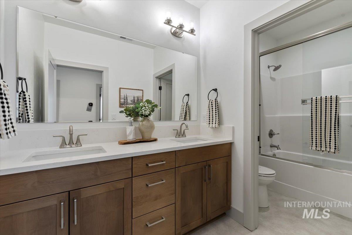 Full bath featuring shower / bath combination with glass door and double vanity