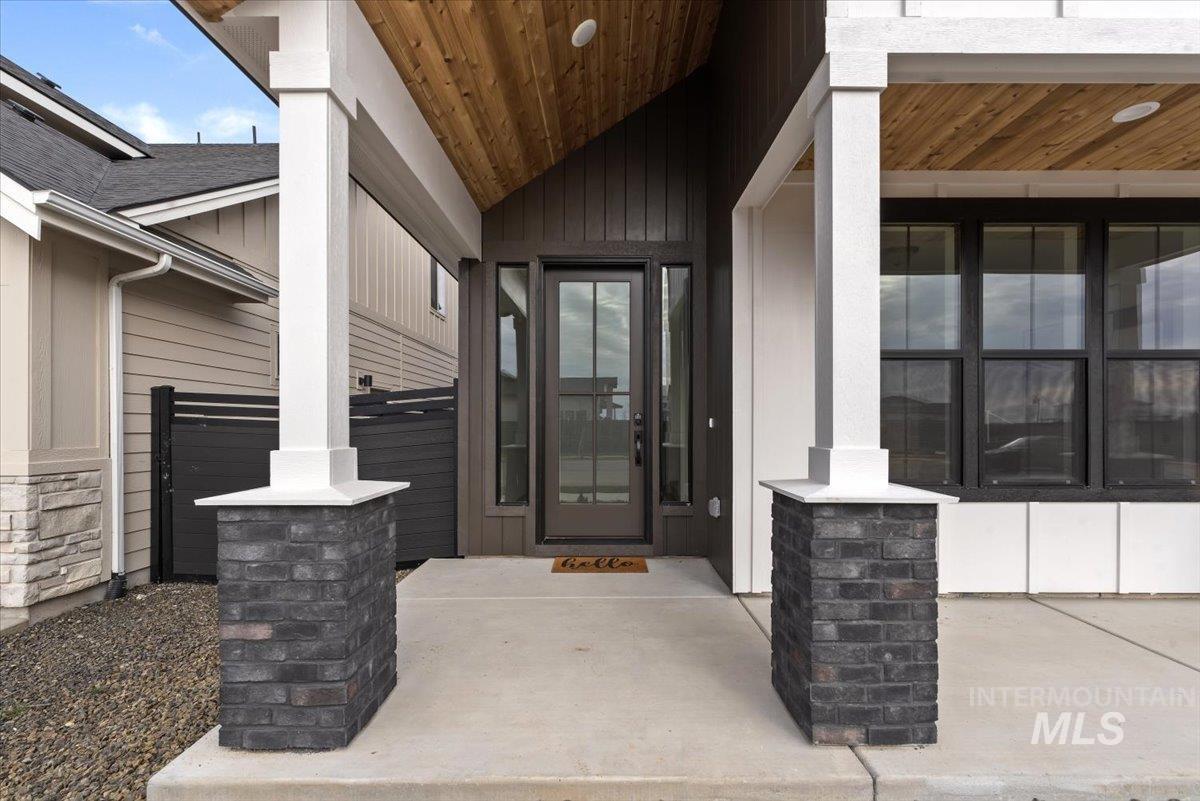Doorway to property with stone siding, a porch, and board and batten siding