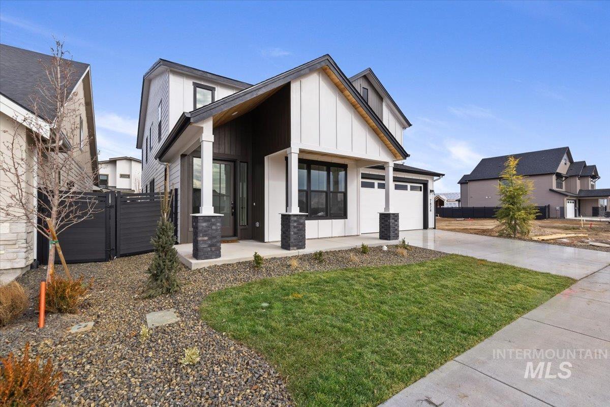 View of front of house with board and batten siding, concrete driveway, a gate, covered porch, and a garage