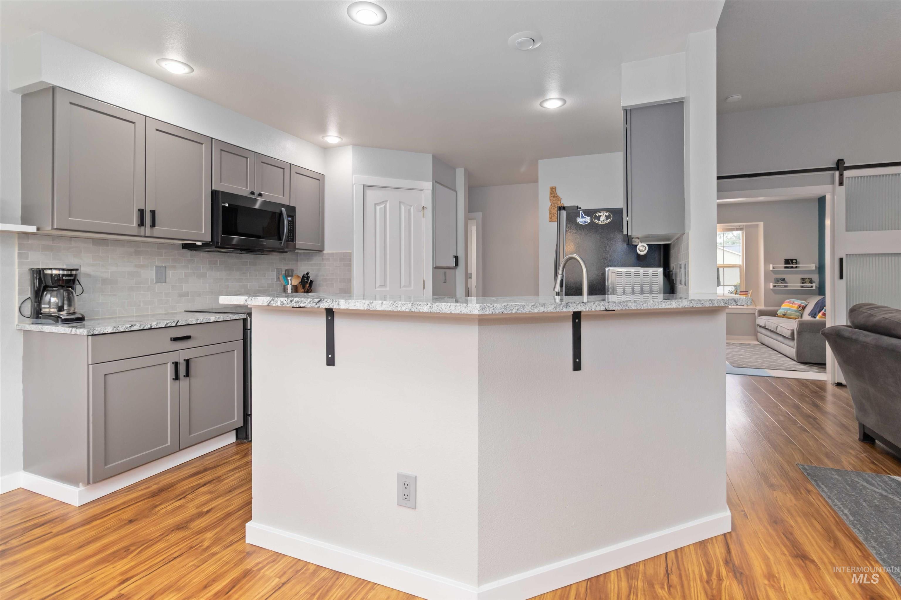 Kitchen featuring gray cabinets, a barn door, decorative backsplash, and recessed lighting