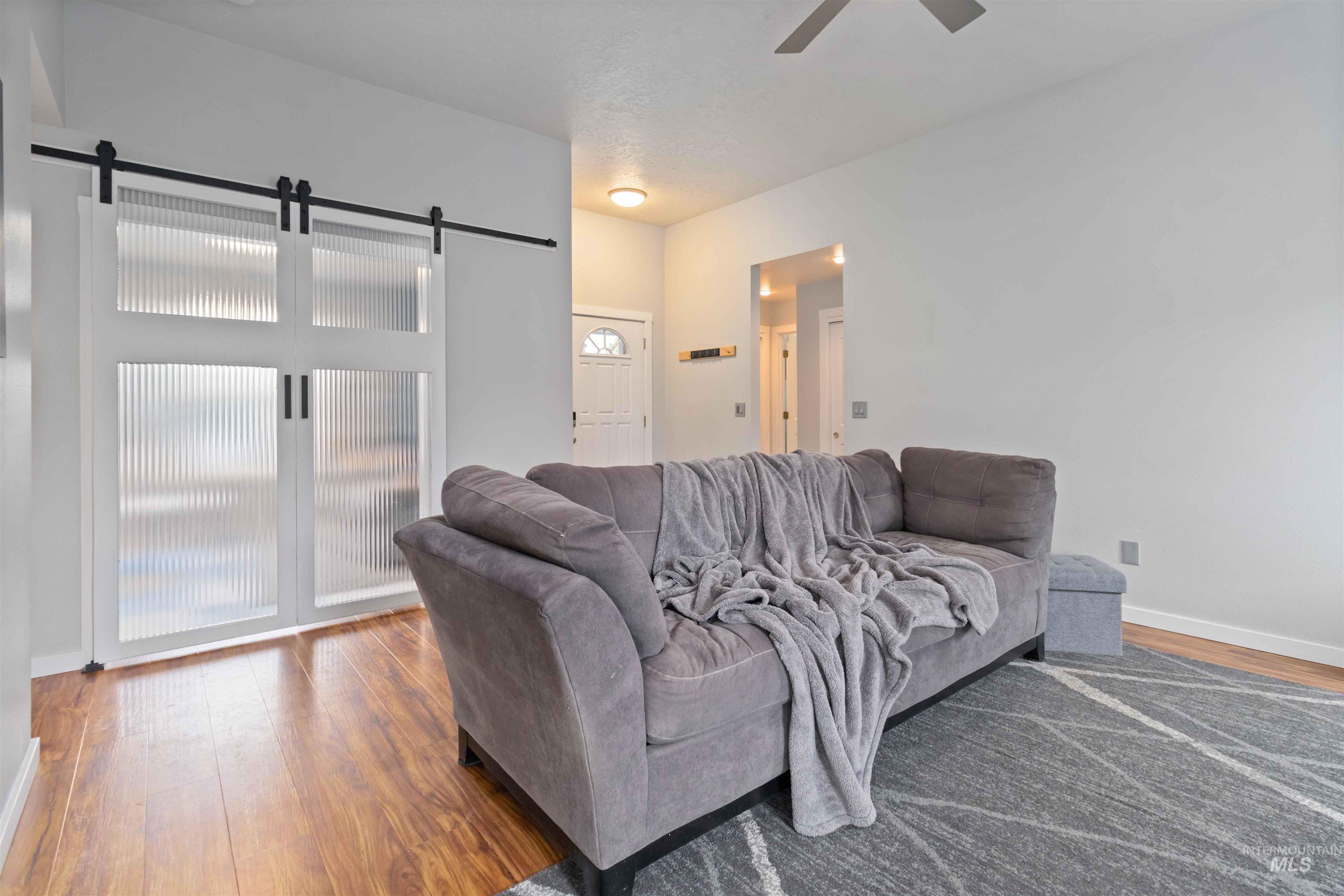 Living room featuring a barn door, wood finished floors, and ceiling fan
