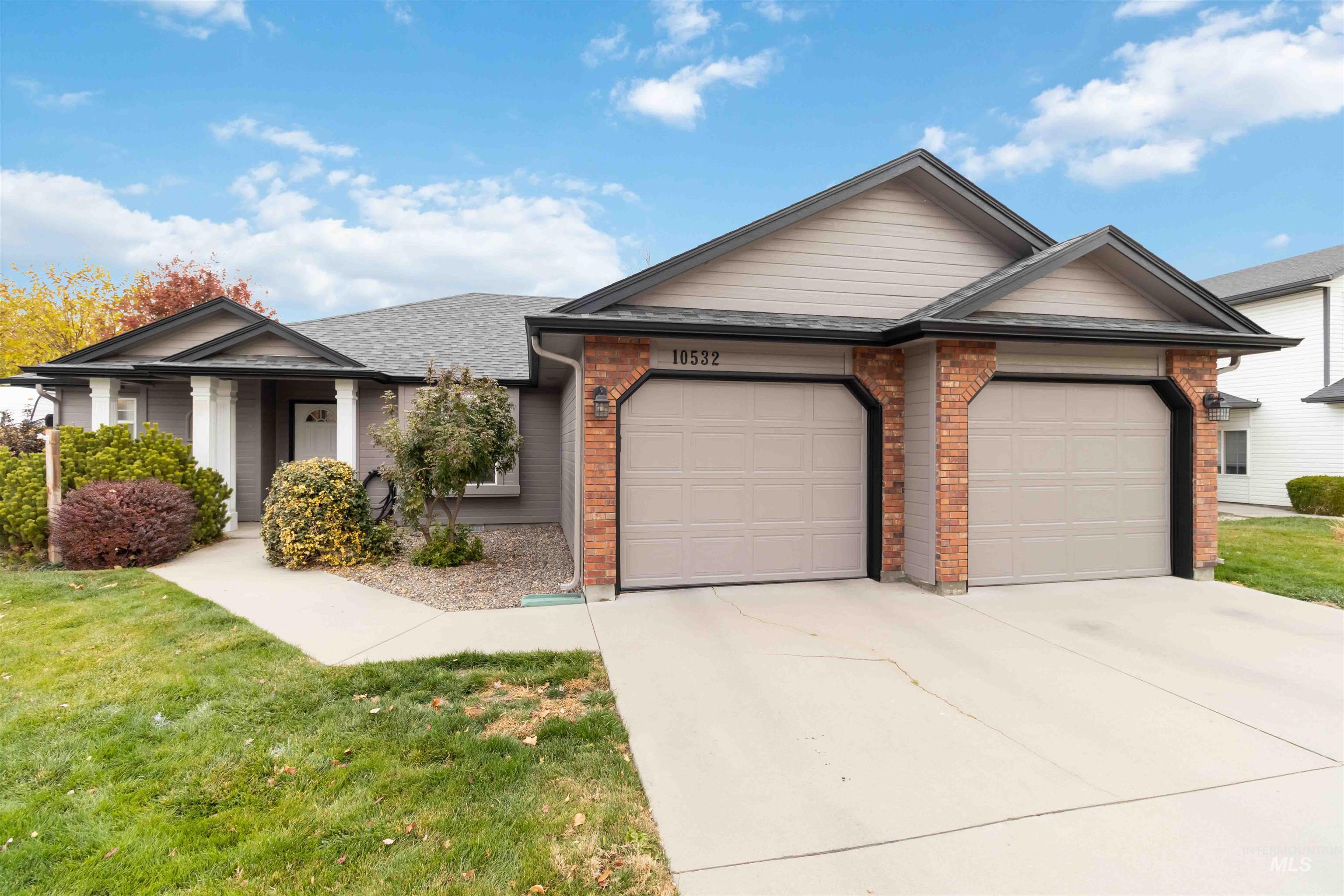 Ranch-style home featuring brick siding, a front yard, an attached garage, driveway, and roof with shingles