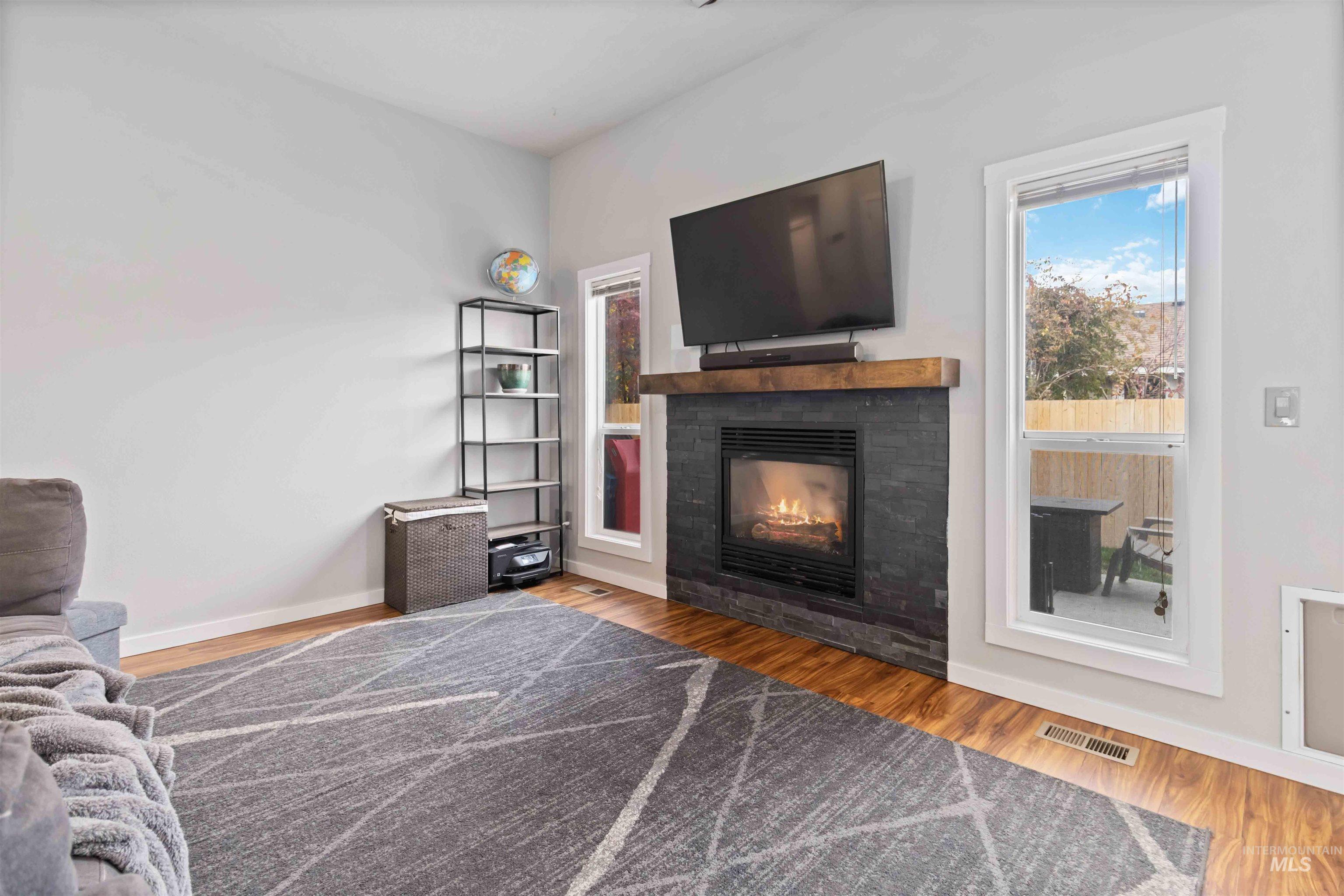Living area featuring wood finished floors and a glass covered fireplace