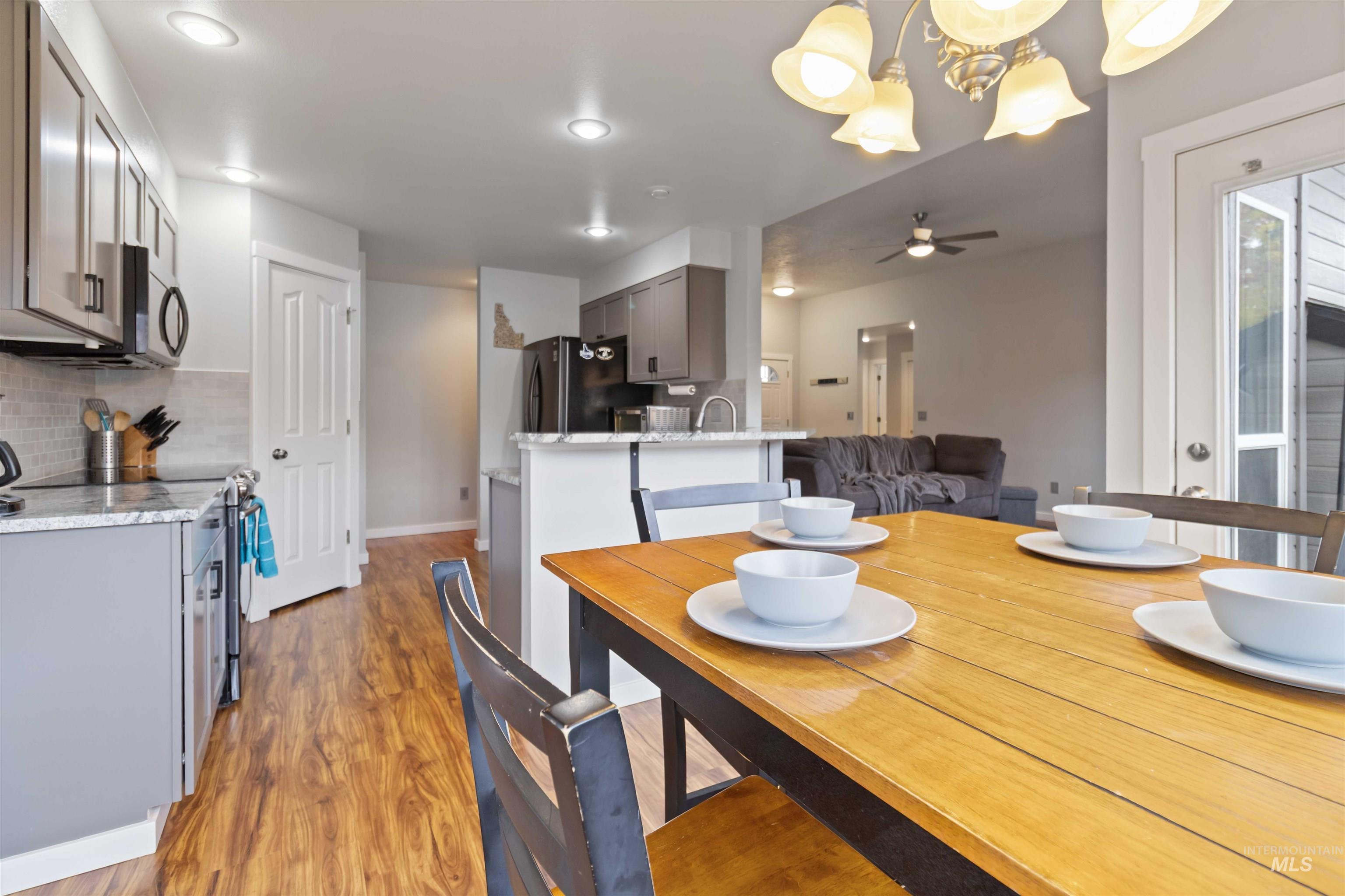 Dining space with light wood-type flooring, a chandelier, and a ceiling fan
