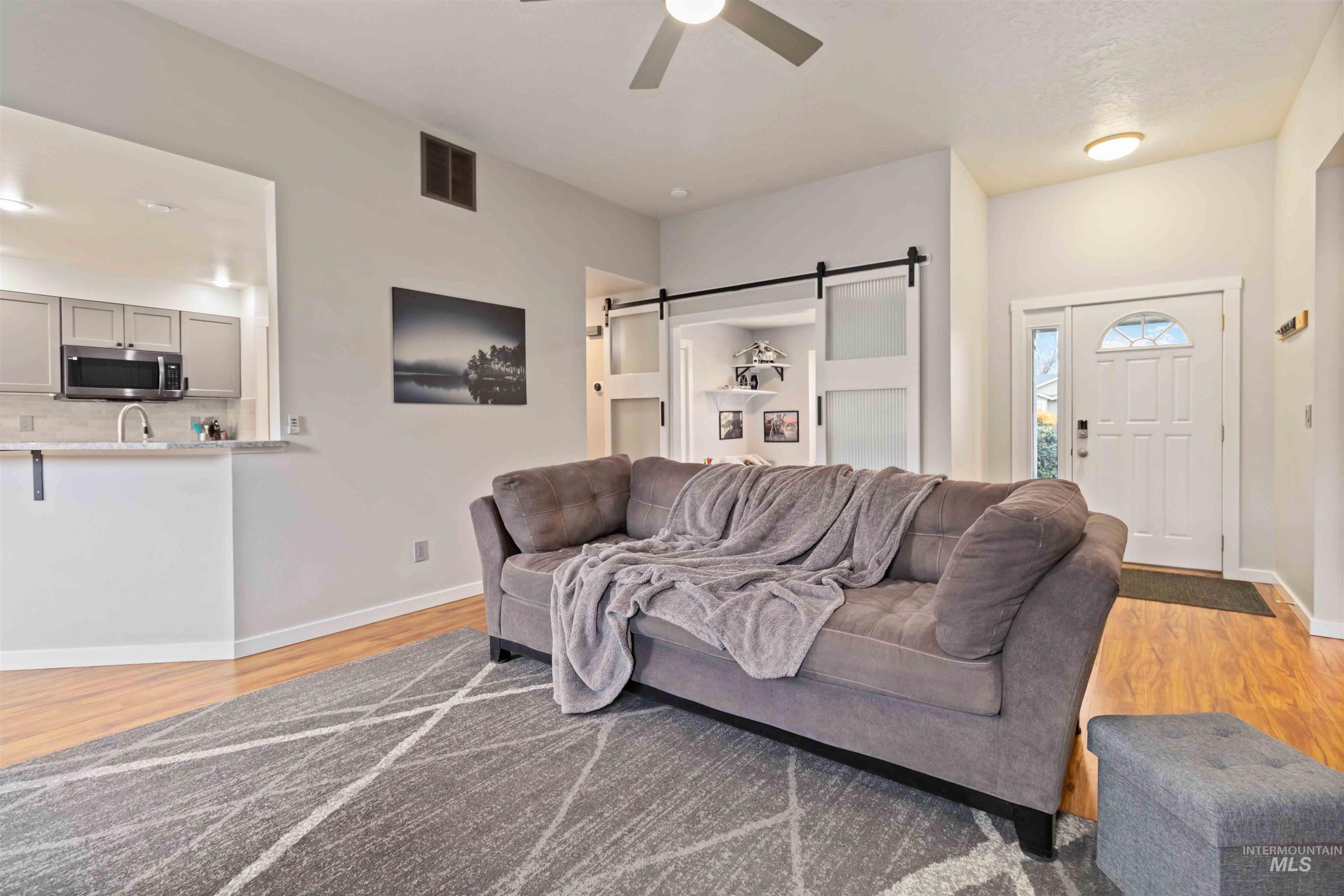 Living area featuring a barn door, light wood finished floors, and ceiling fan