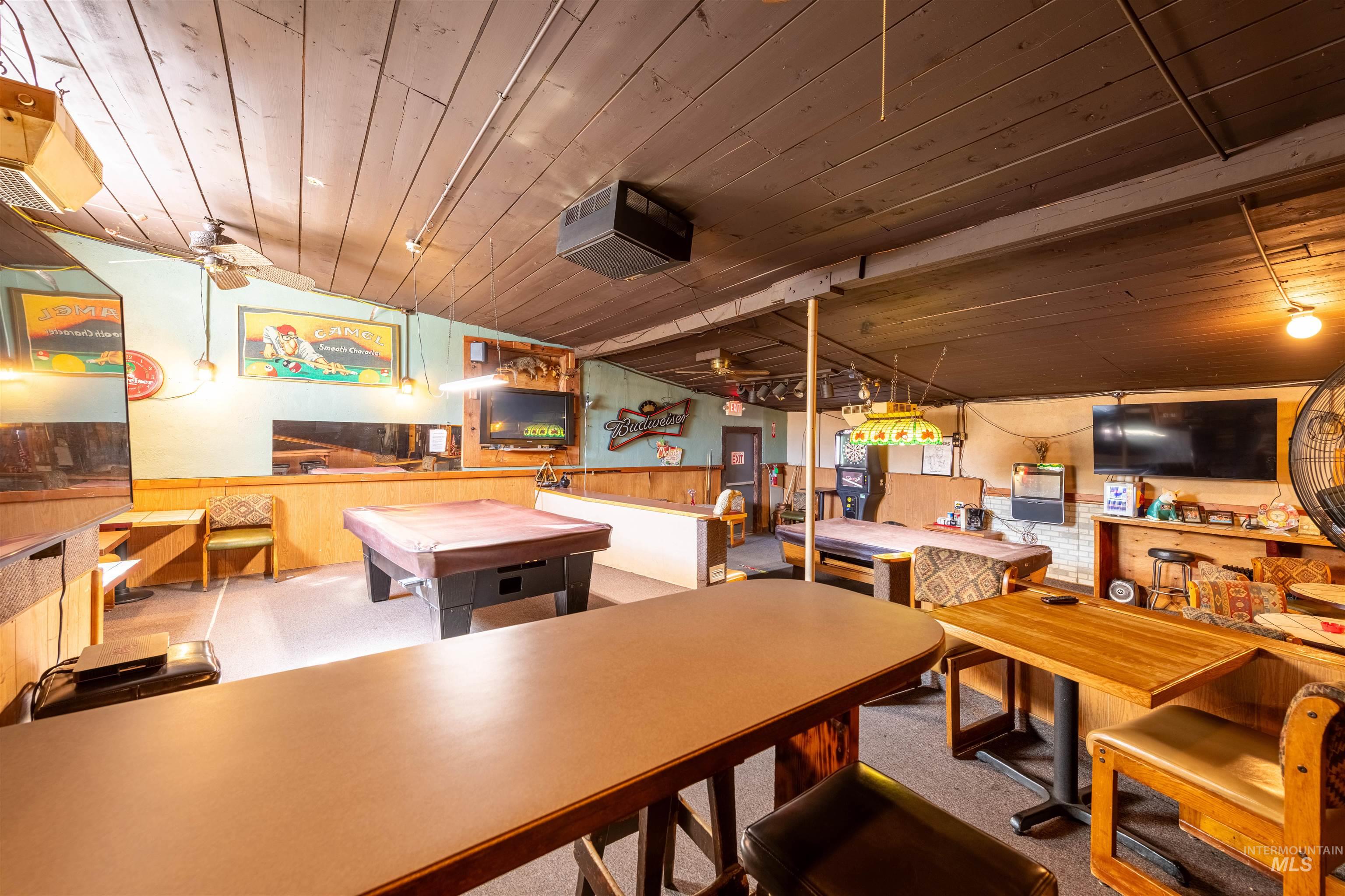 Carpeted dining space featuring wood walls, wainscoting, wood ceiling, and vaulted ceiling