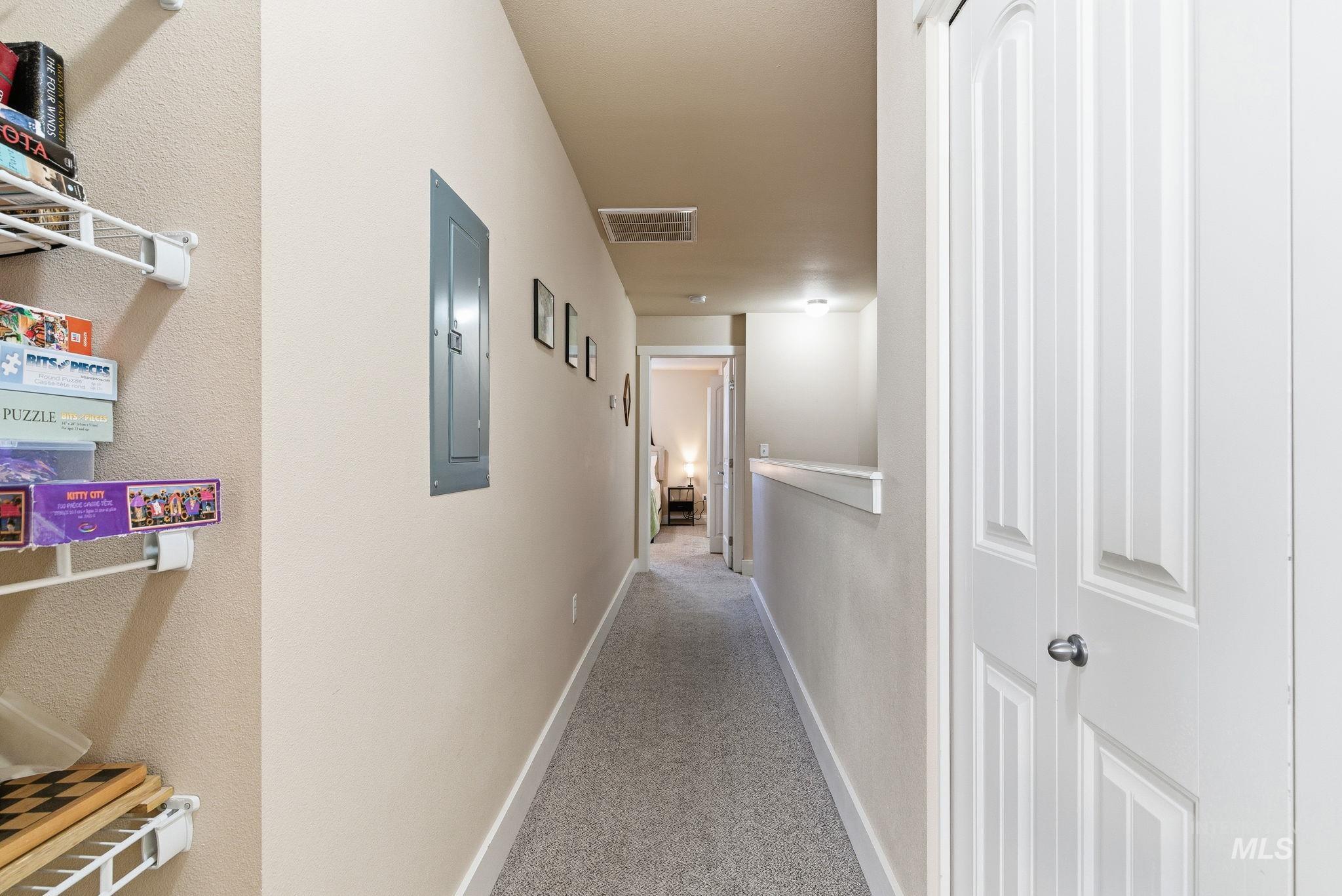 Hall with light colored carpet and electric panel