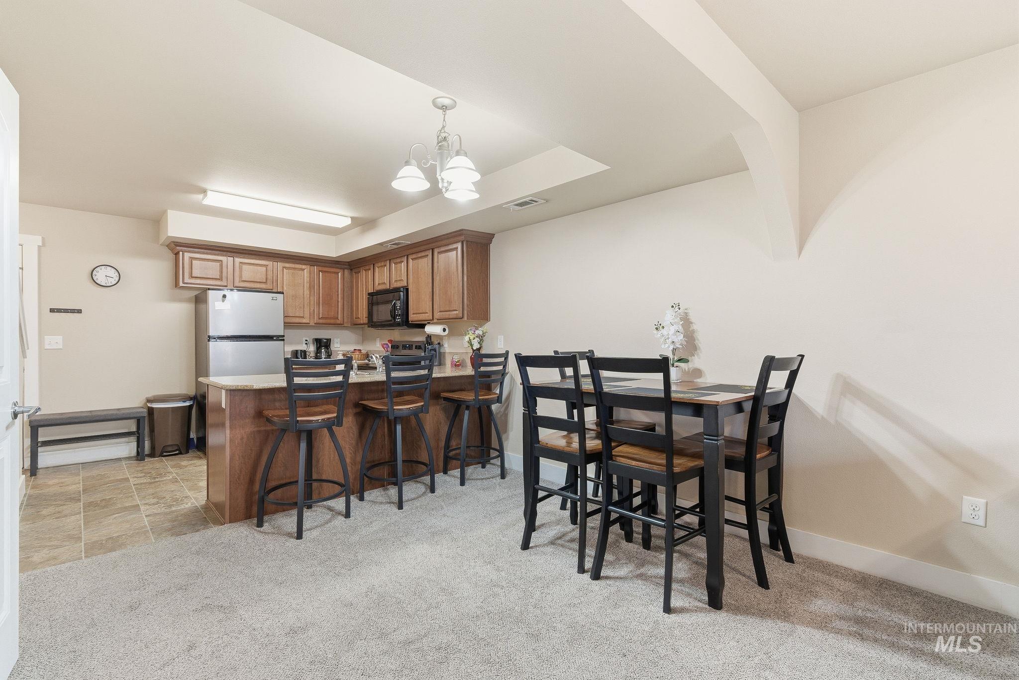 Kitchen with light carpet, a chandelier, hanging light fixtures, a breakfast bar area, and a peninsula