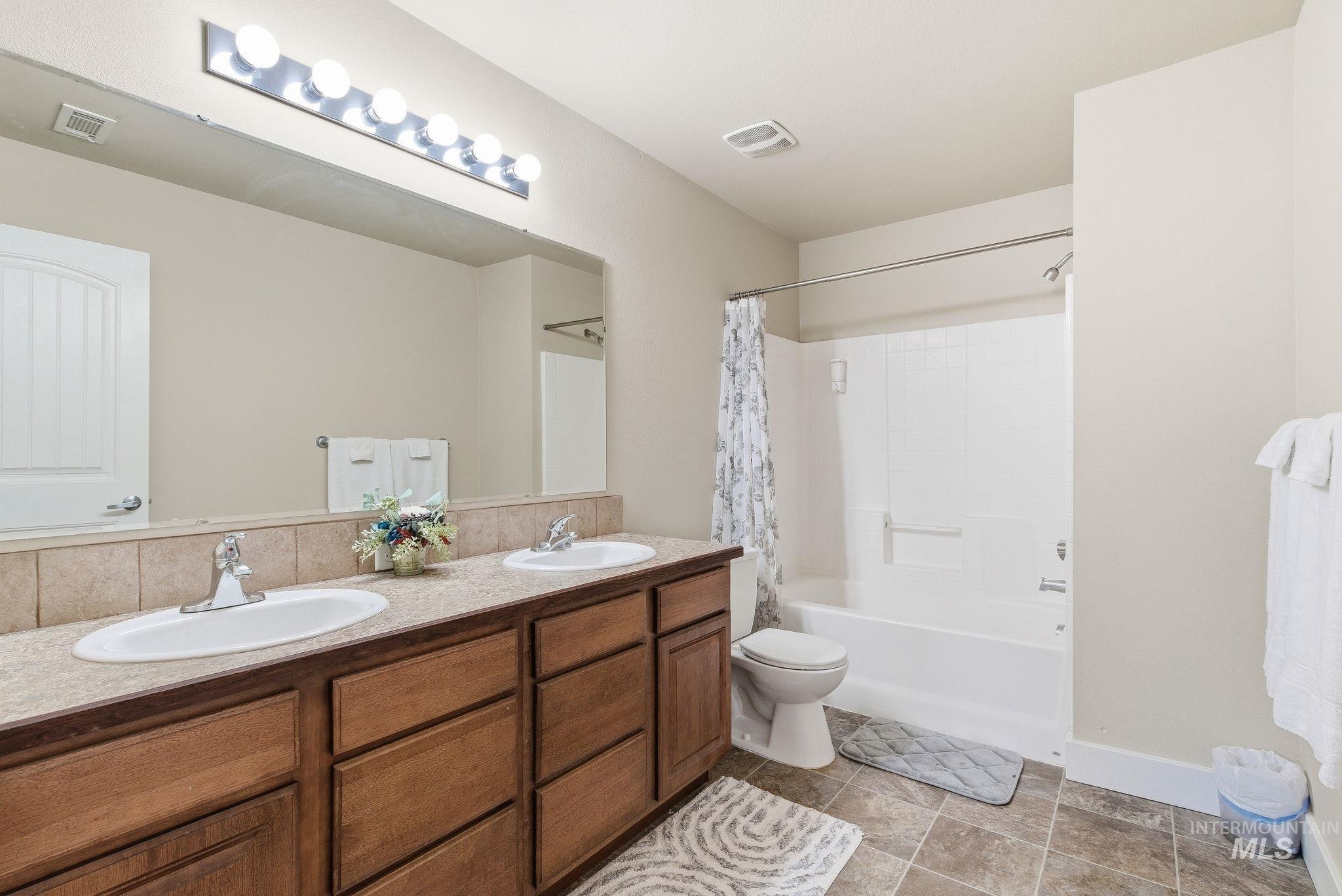 Bathroom with double vanity and shower / bath combo with shower curtain