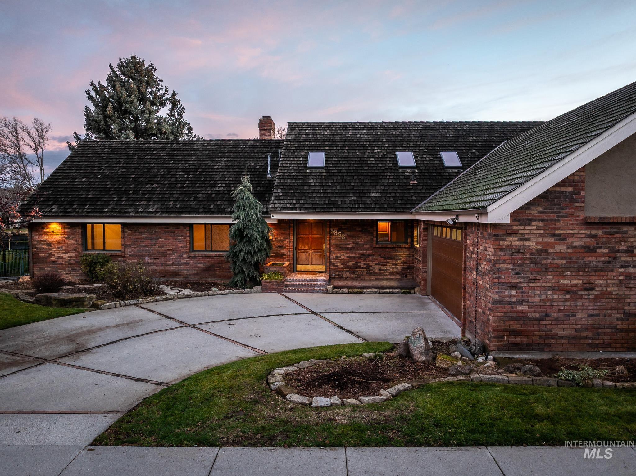 Back of property featuring brick siding, concrete driveway, and a chimney