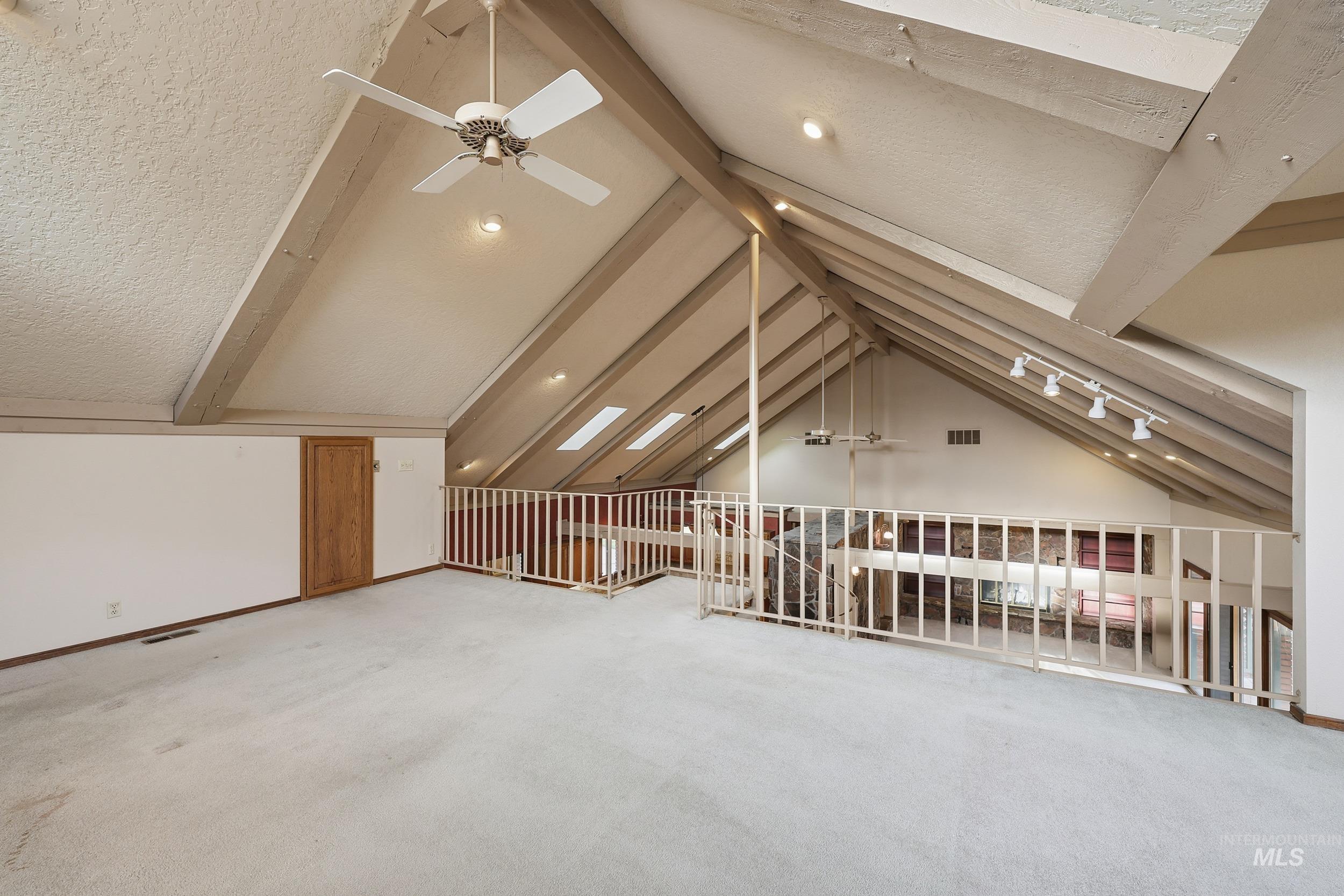 Bonus room with a ceiling fan, light carpet, and a textured ceiling