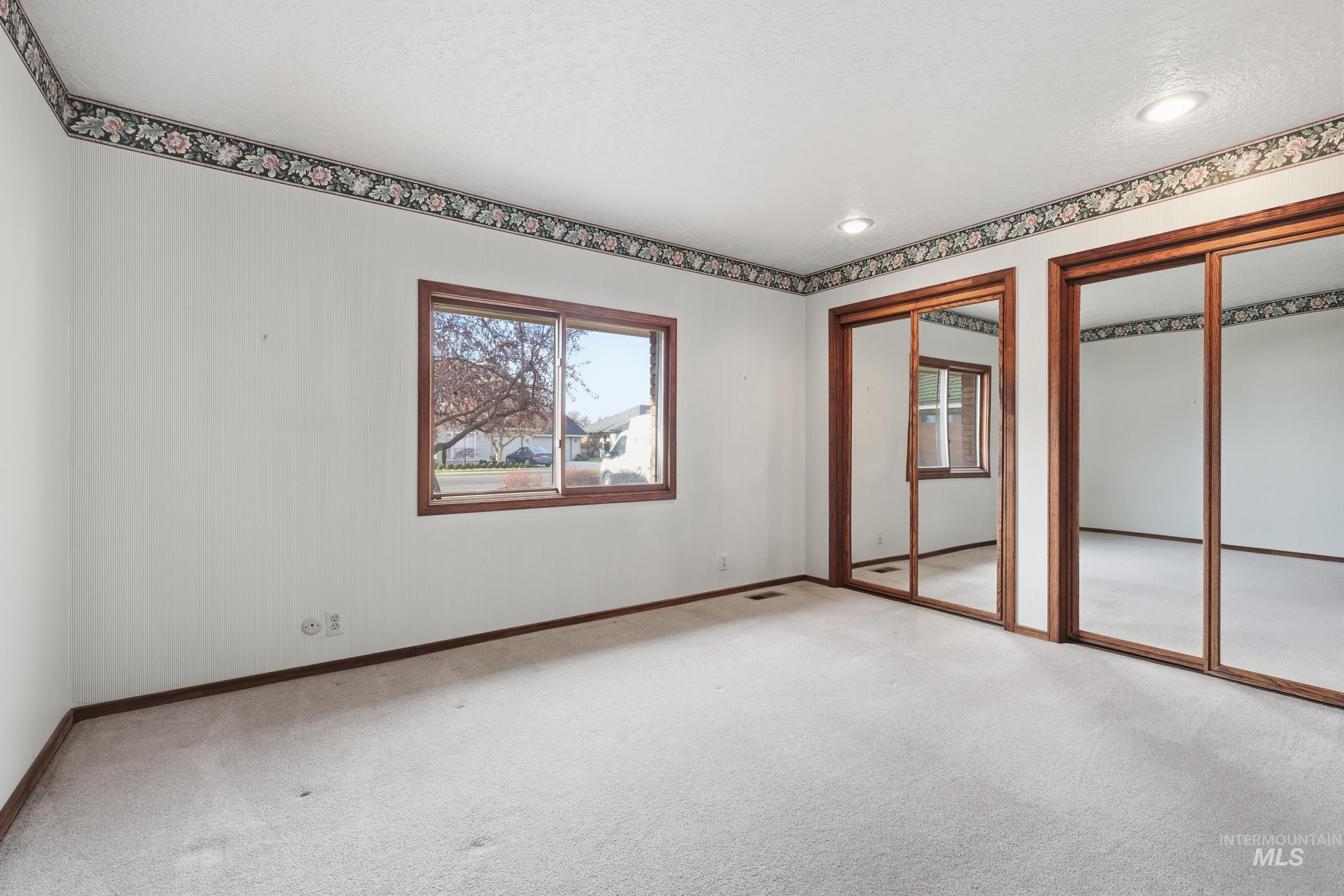 Unfurnished bedroom with multiple closets, carpet flooring, and multiple windows