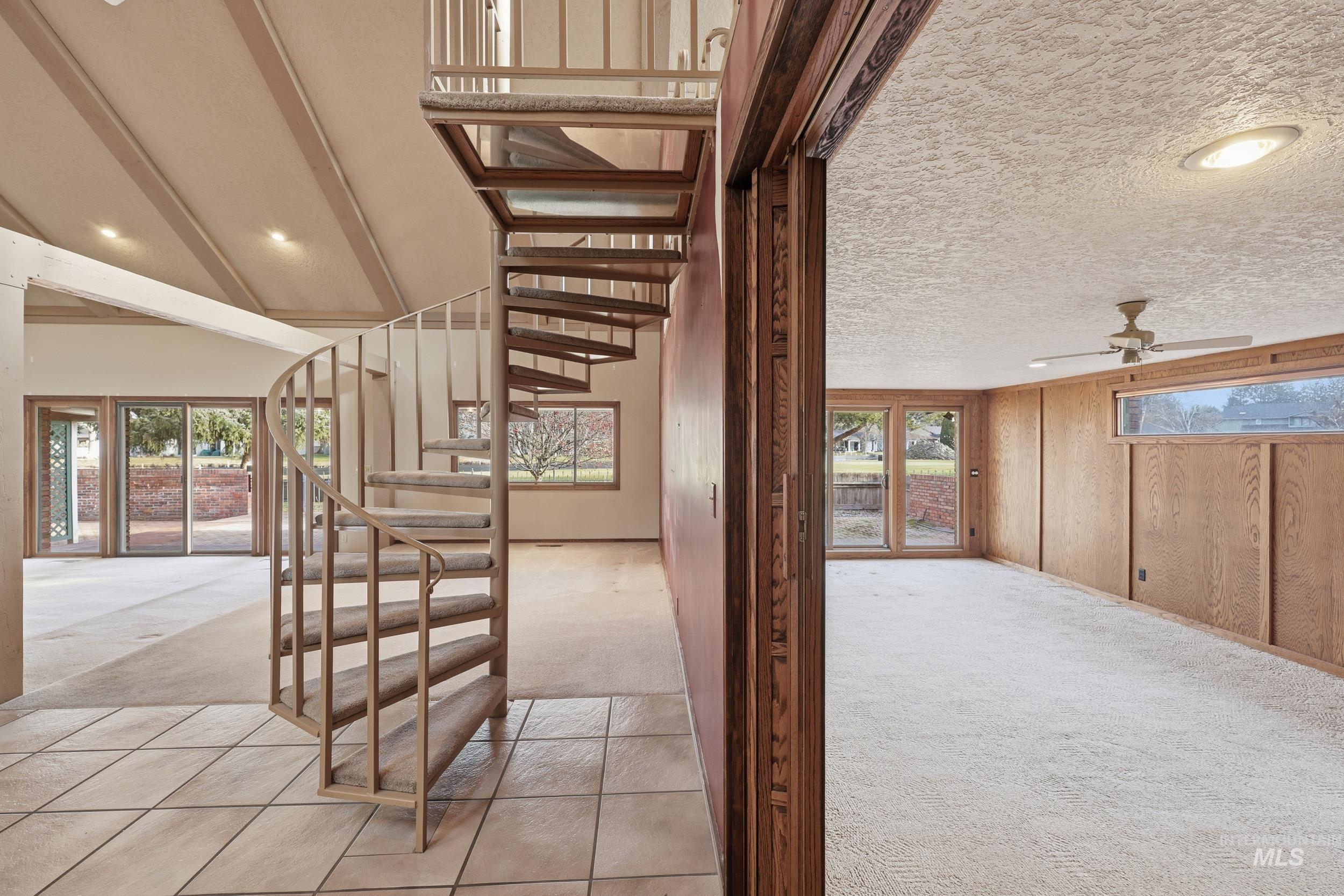 Stairway with carpet flooring, recessed lighting, ceiling fan, wood walls, and a textured ceiling