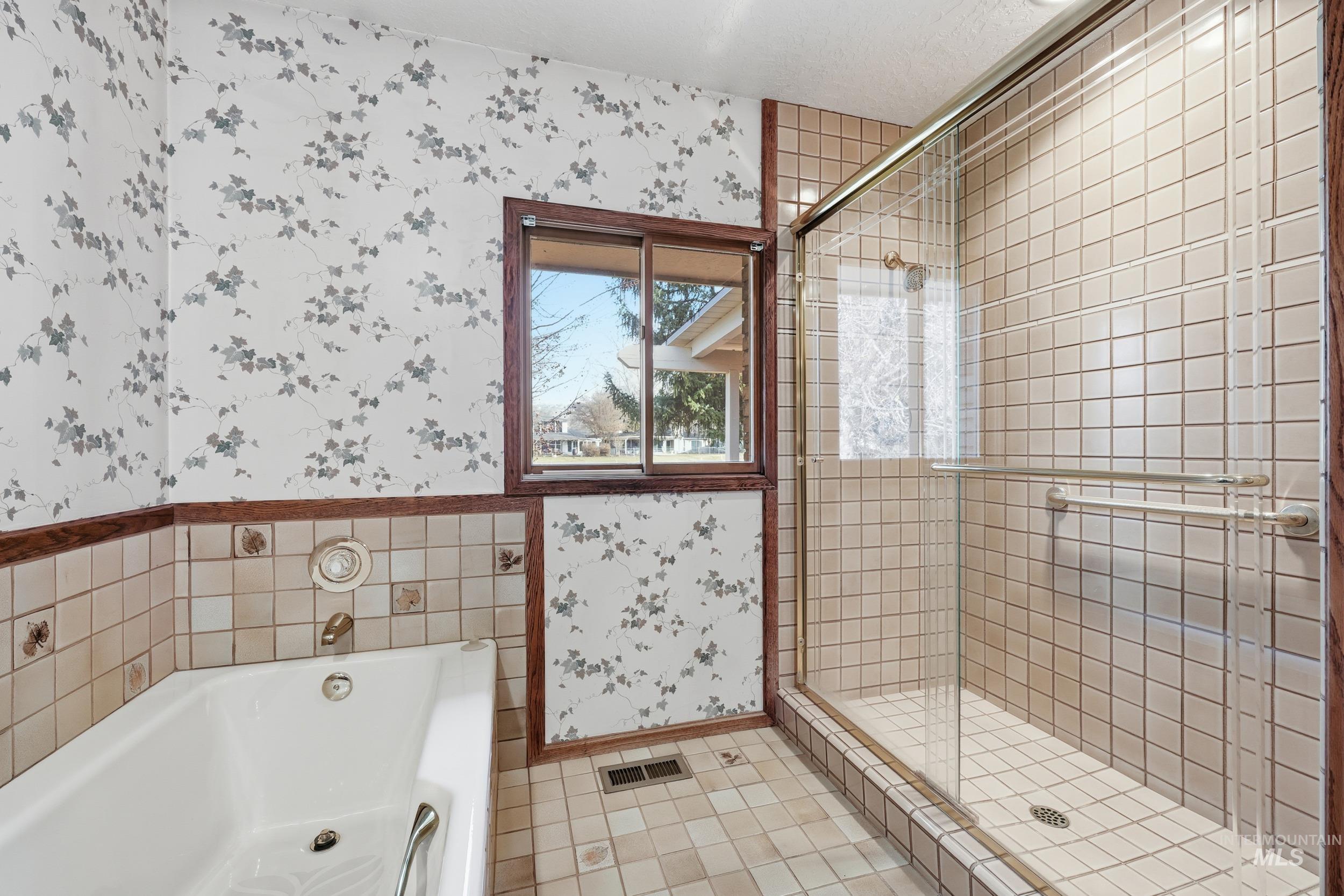 Full bathroom featuring wallpapered walls, a garden tub, a stall shower, and light tile patterned floors