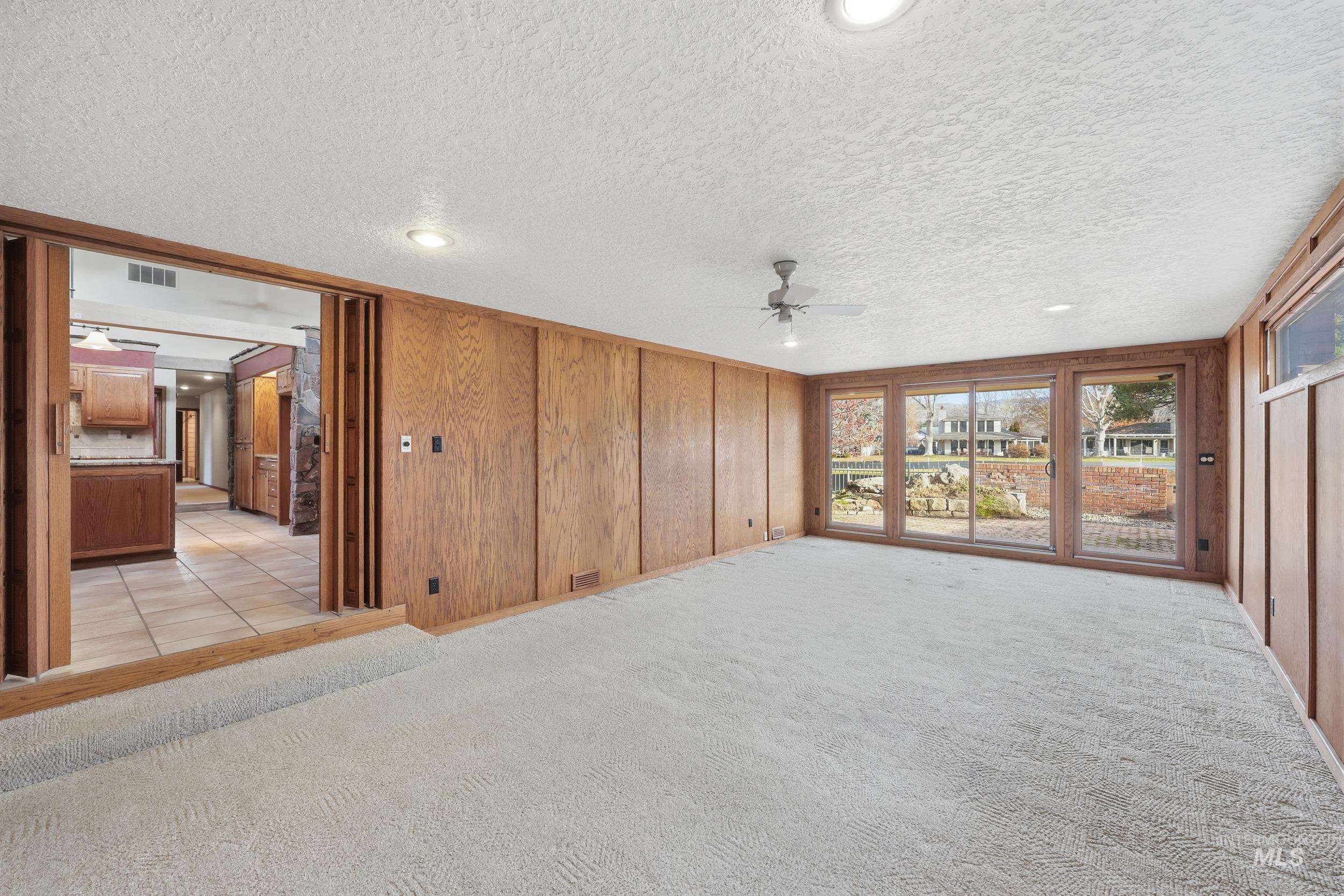 Unfurnished living room with recessed lighting, a ceiling fan, a textured ceiling, wooden walls, and light colored carpet