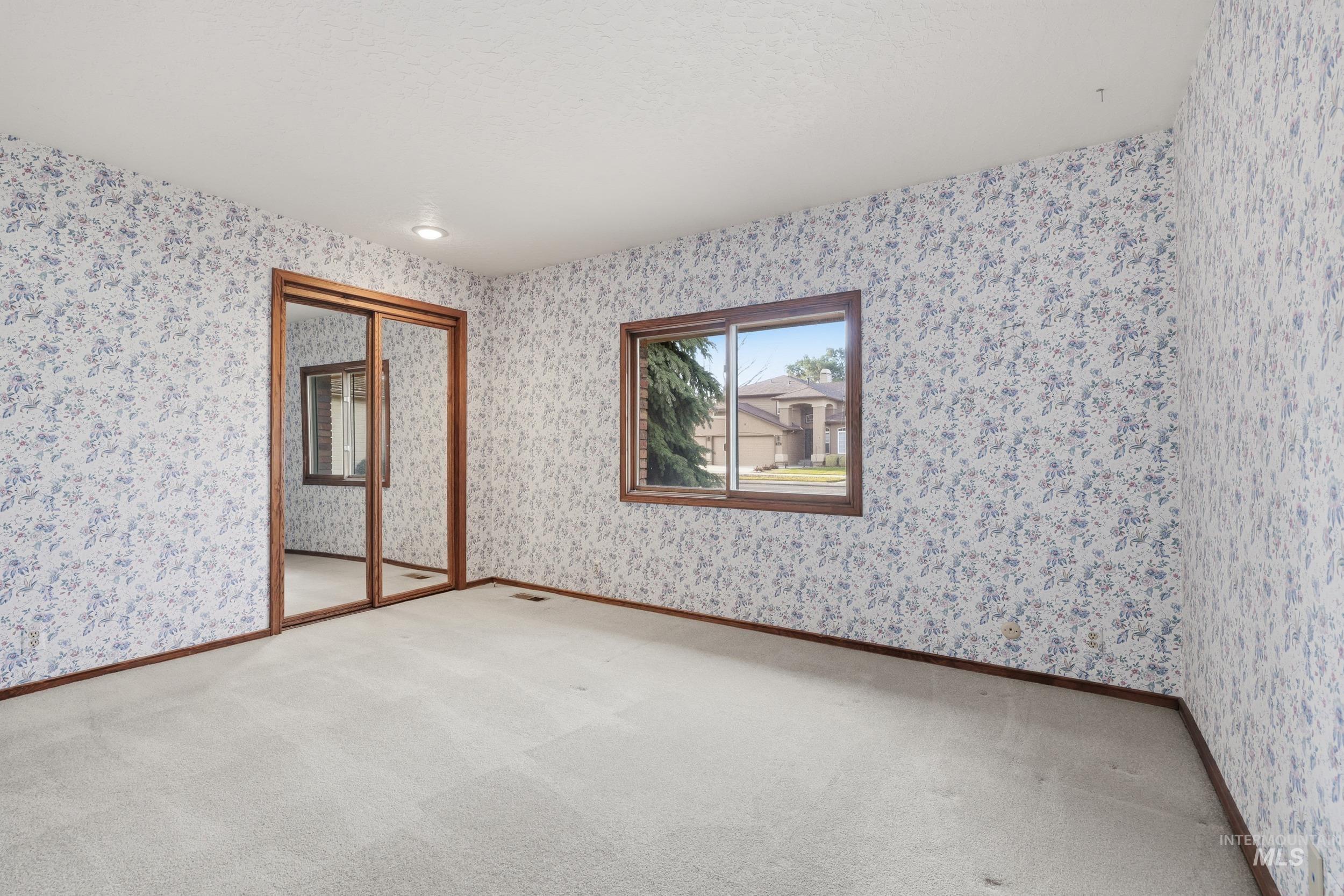 Carpeted spare room with wallpapered walls and baseboards