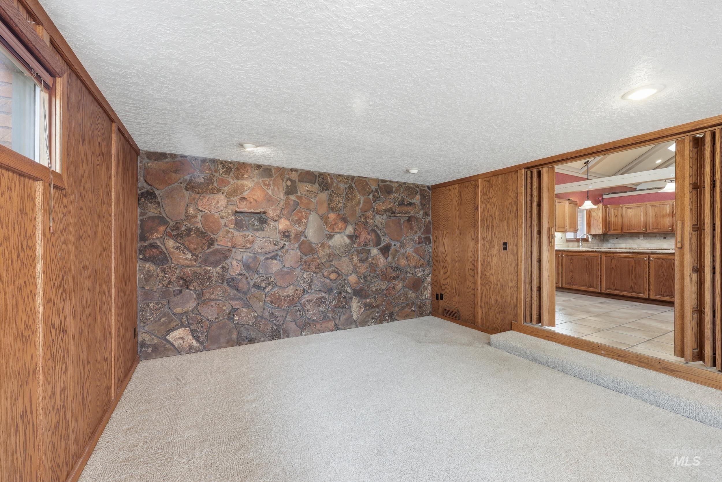 Empty room with light colored carpet and a textured ceiling