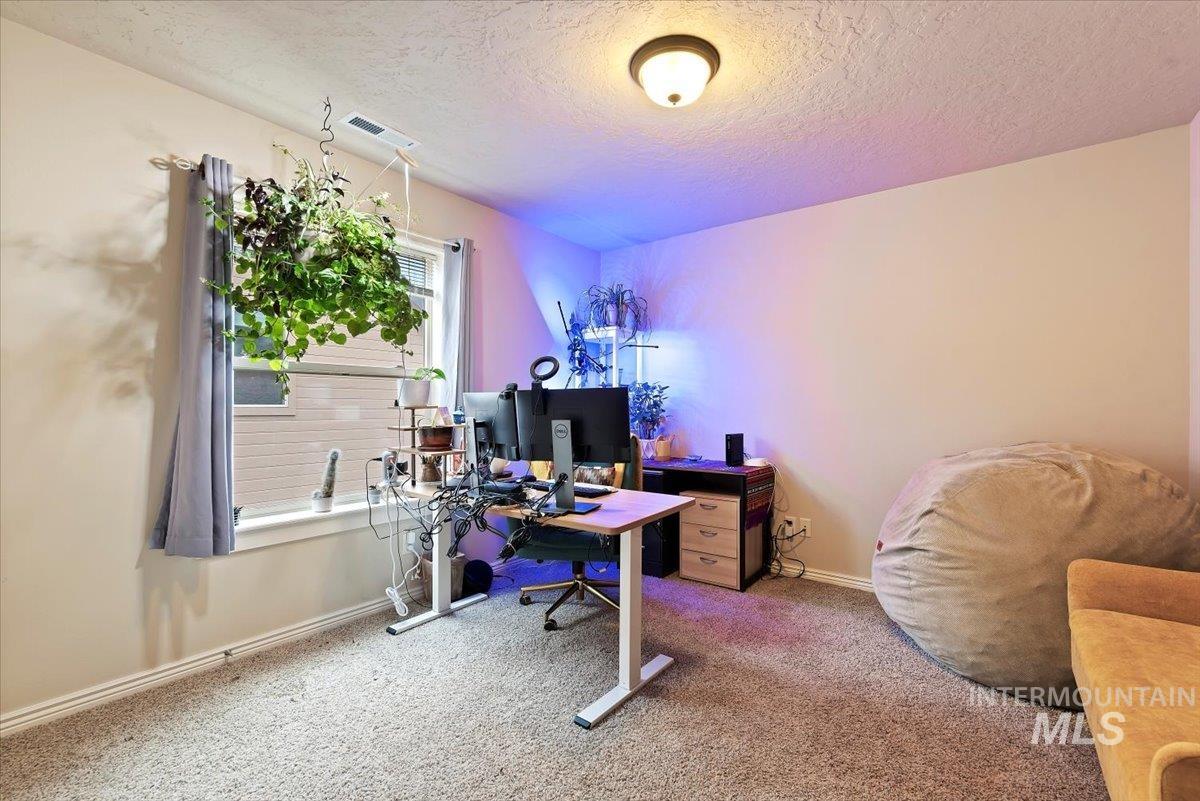 Carpeted office featuring baseboards and a textured ceiling