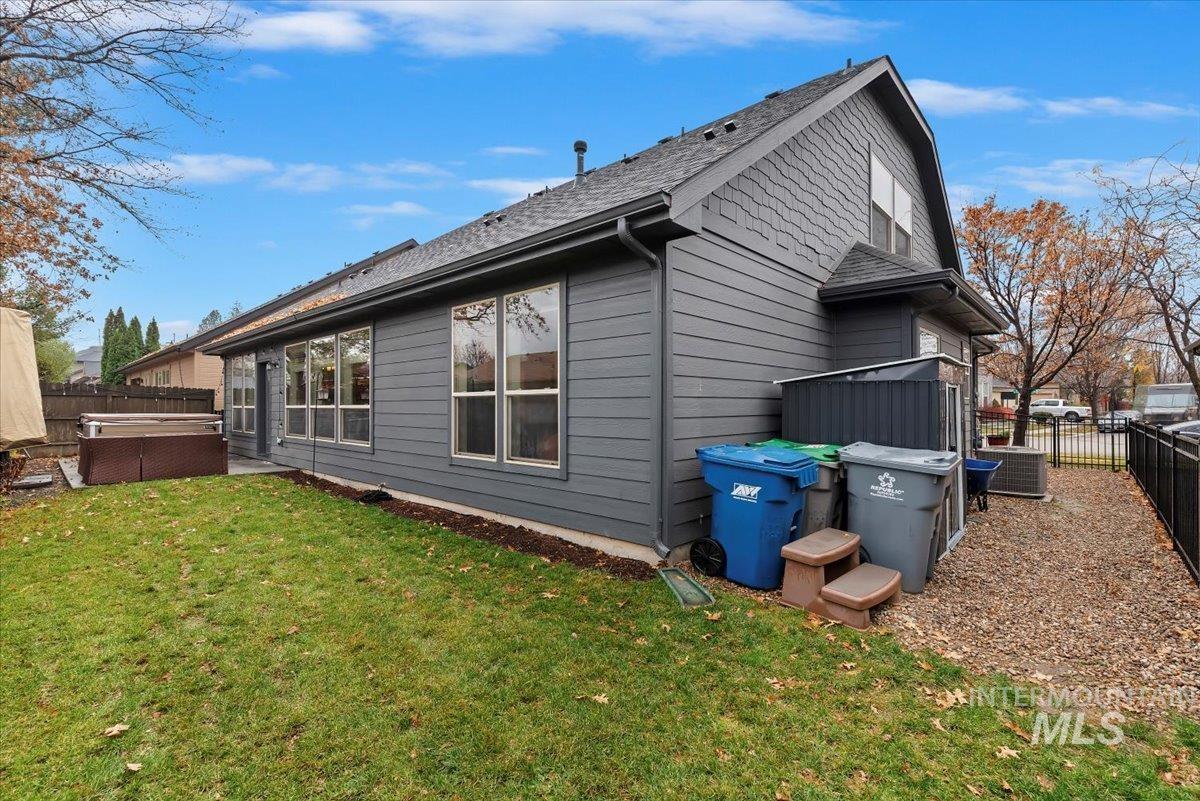 Rear view of house with a fenced backyard, a hot tub, roof with shingles, and a patio