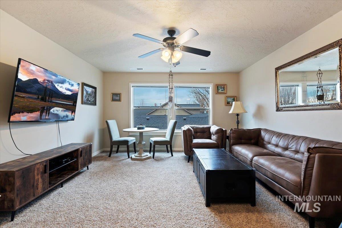 Living room with light carpet, a textured ceiling, and ceiling fan