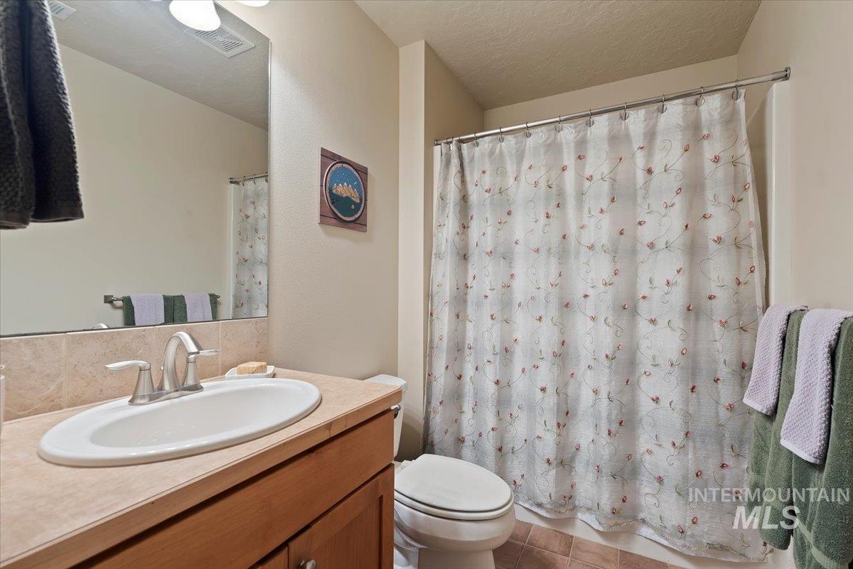 Full bathroom with vanity, curtained shower, a textured ceiling, and light tile patterned floors