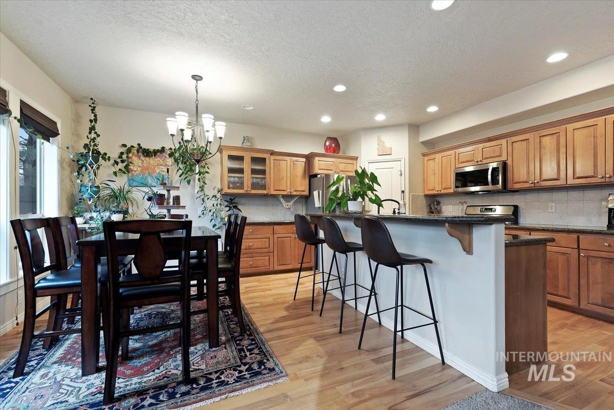 Kitchen with a breakfast bar area, light wood-style floors, a textured ceiling, stainless steel appliances, and a chandelier