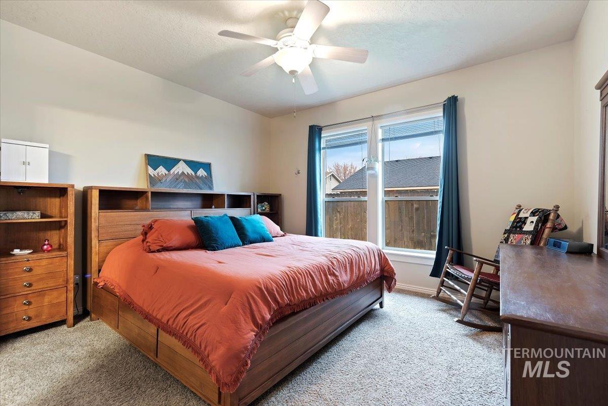 Bedroom featuring light colored carpet, a ceiling fan, and a textured ceiling
