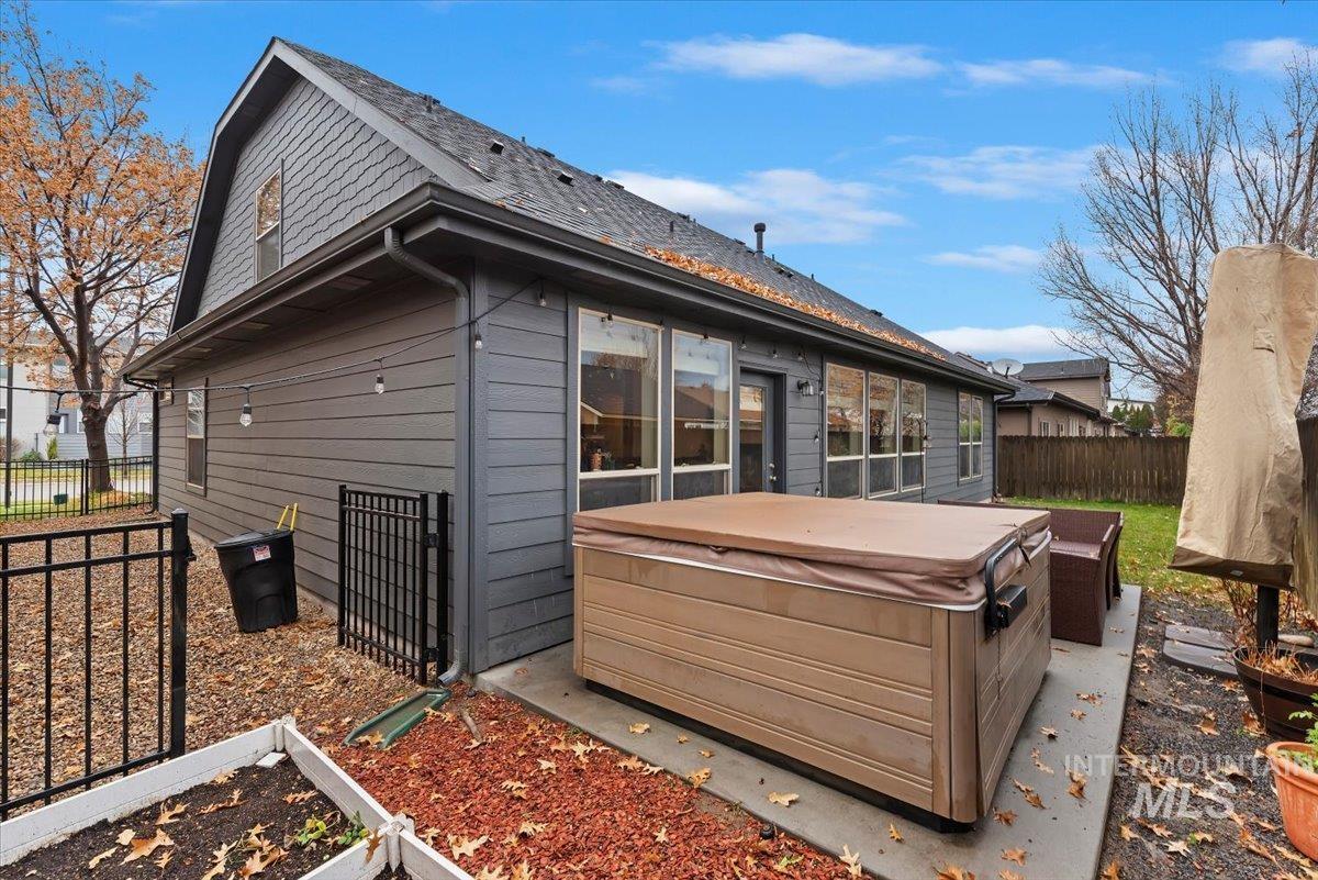 Rear view of house with a hot tub, a shingled roof, and a patio