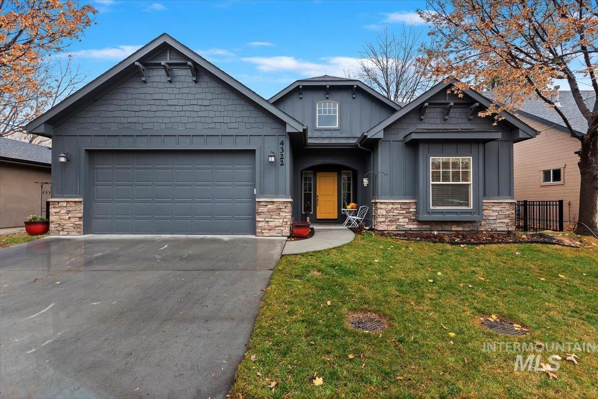 Craftsman-style house featuring board and batten siding, stone siding, a front lawn, and concrete driveway