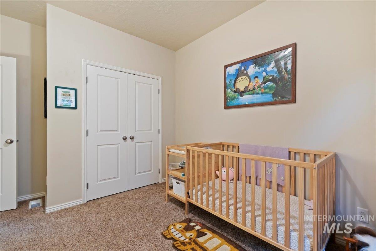 Carpeted bedroom with a nursery area and a closet