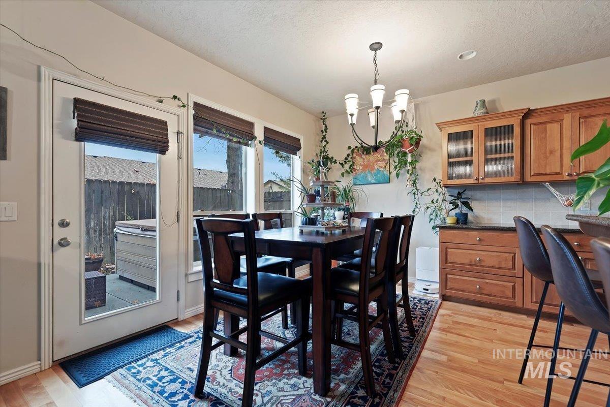 Dining area featuring light wood finished floors, a chandelier, and a textured ceiling